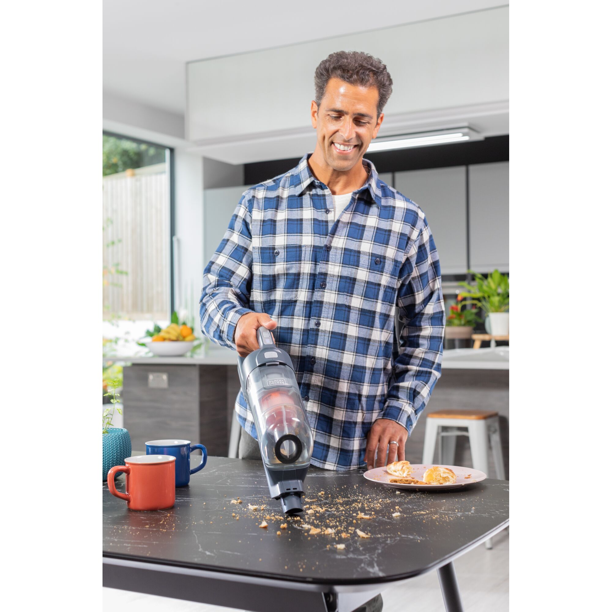 BLACKDECKER BHFEA520J handheld vacuum cleaning crumbs from a black table in a kitchen setting.