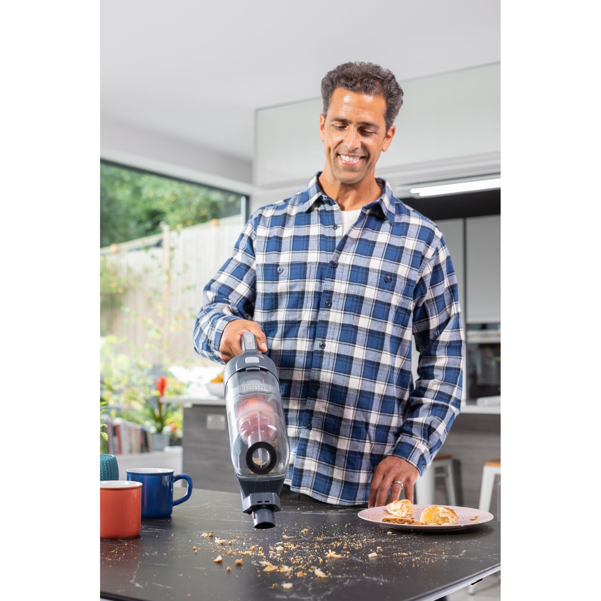 BLACKDECKER BHFEA520J cordless vacuum cleaning crumbs on kitchen table, male model in plaid shirt.