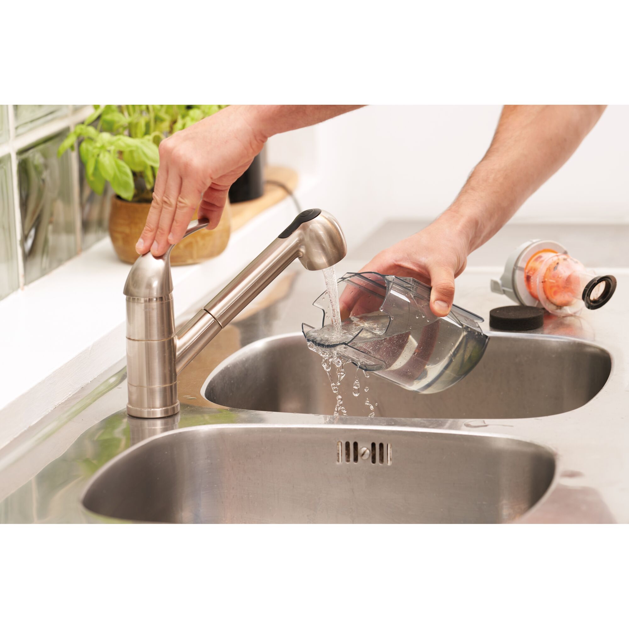 BLACKDECKER BHFEA520J vacuum dustbin being rinsed with water in a kitchen sink, close-up.