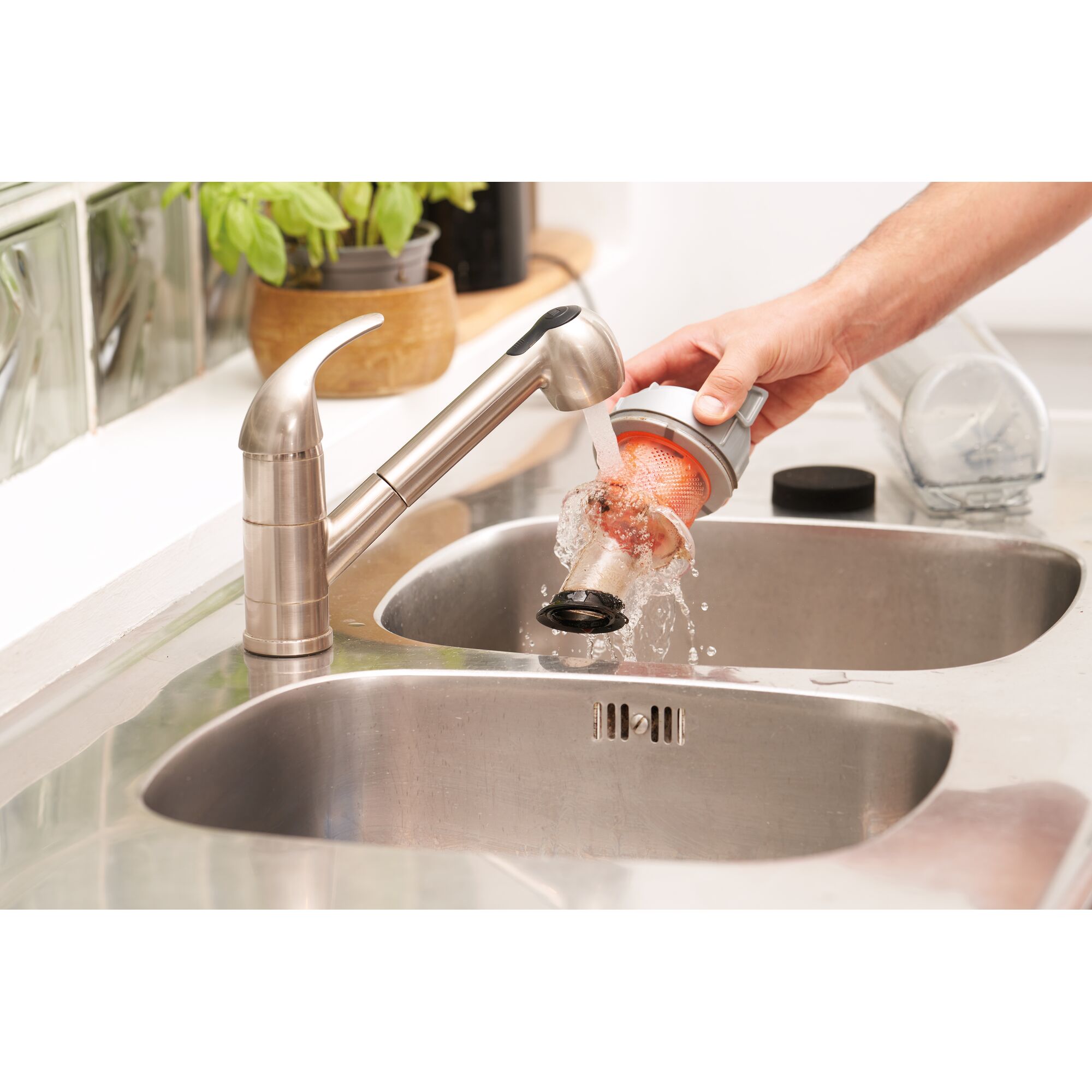 BLACKDECKER BHFEA520J vacuum filter being rinsed under kitchen faucet over stainless steel sink.