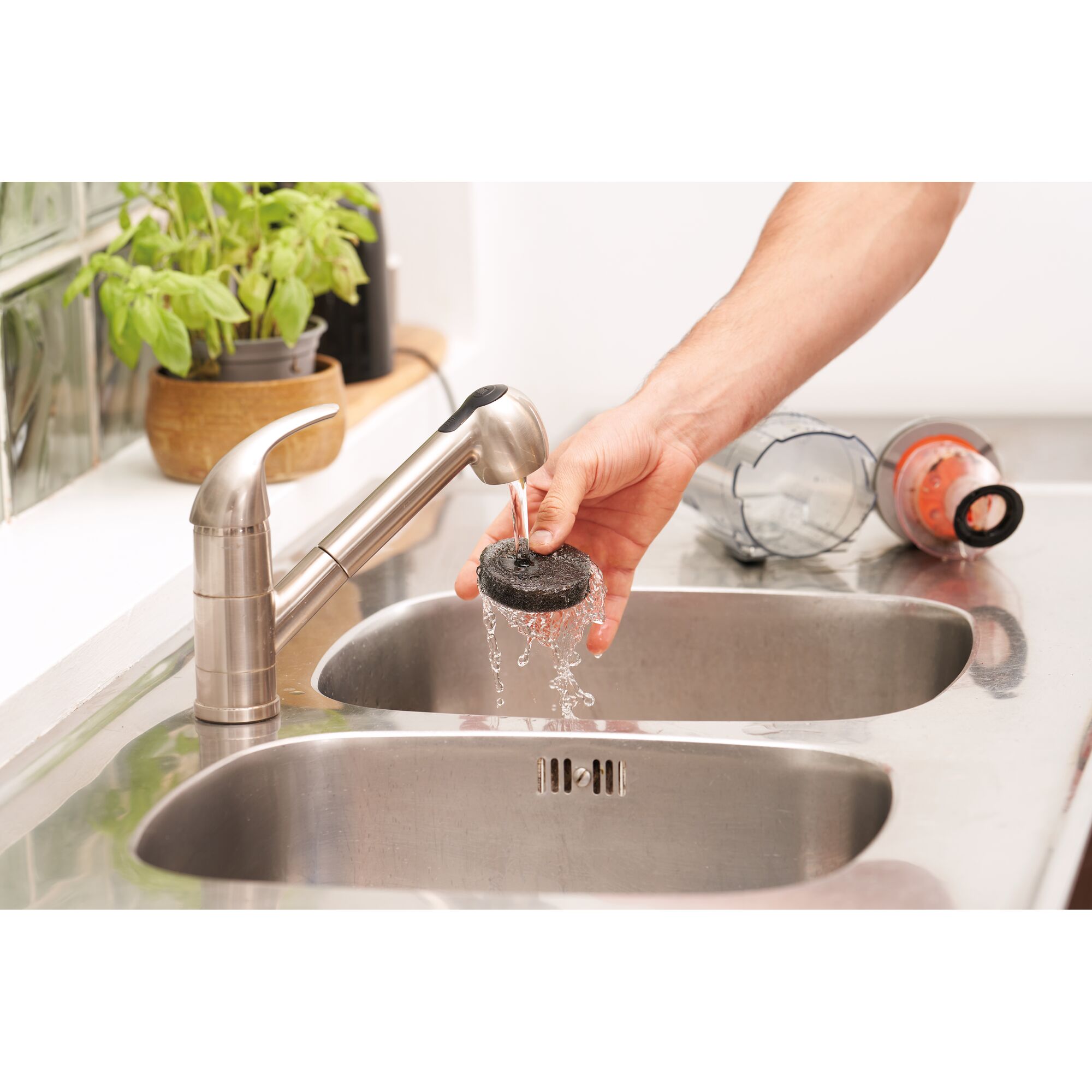 BLACK+DECKER BHFEA520J vacuum filter being rinsed under kitchen faucet, parts on sink, photo from above.