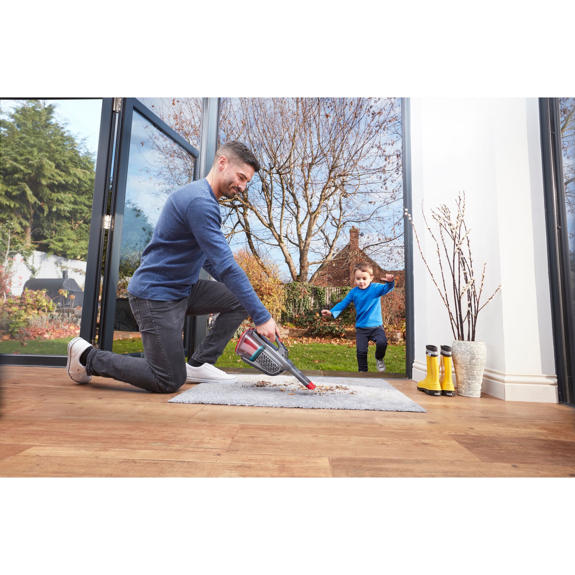 BLACKDECKER BHHV315J handheld vacuum being used to clean dirt on a rug near an open doorway.