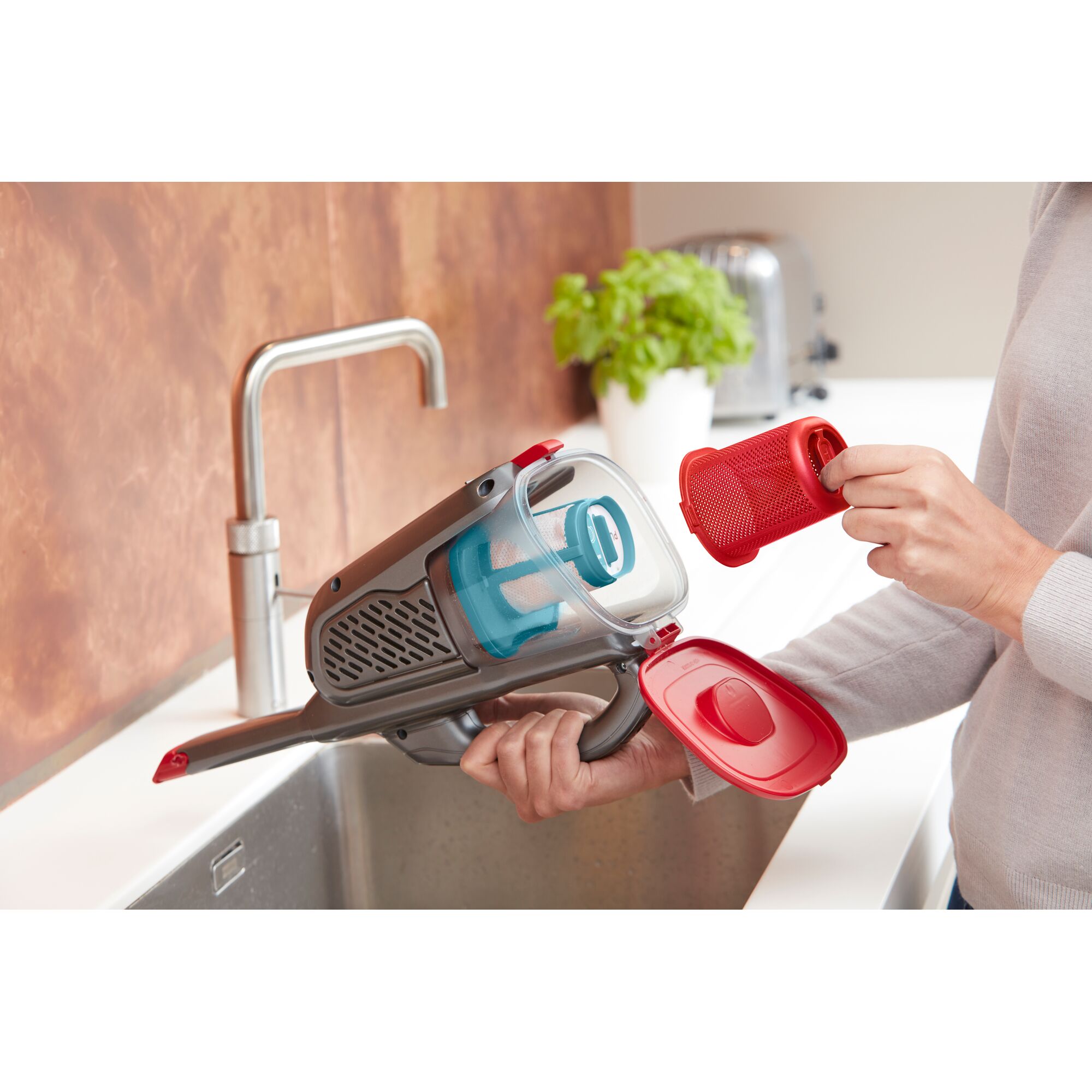 BLACKDECKER BHHV315J handheld vacuum showing filter removal over kitchen sink.