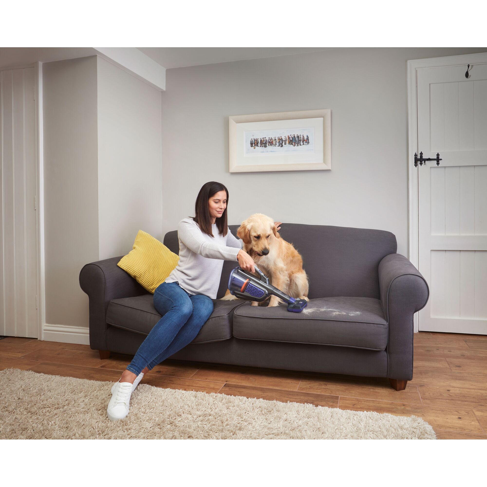 BLACKDECKER BHHV520BFP07 handheld vacuum used to clean pet hair from a gray sofa in a living room.