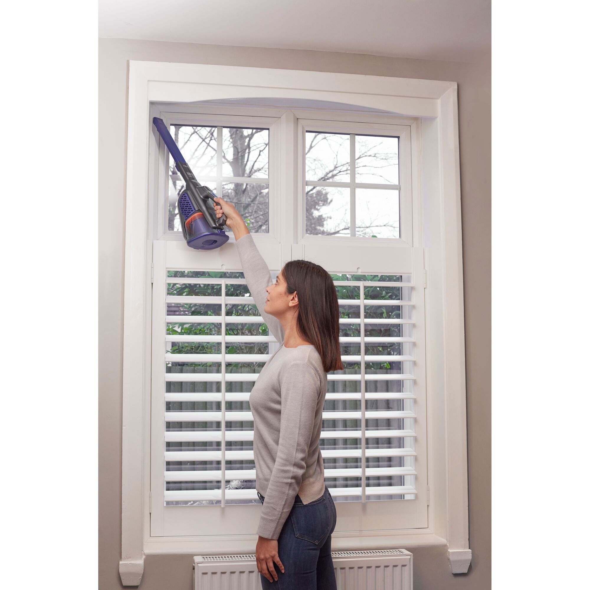 Person using BLACKDECKER BHHV520BFP07 handheld vacuum cleaner with long nozzle to clean window frame.