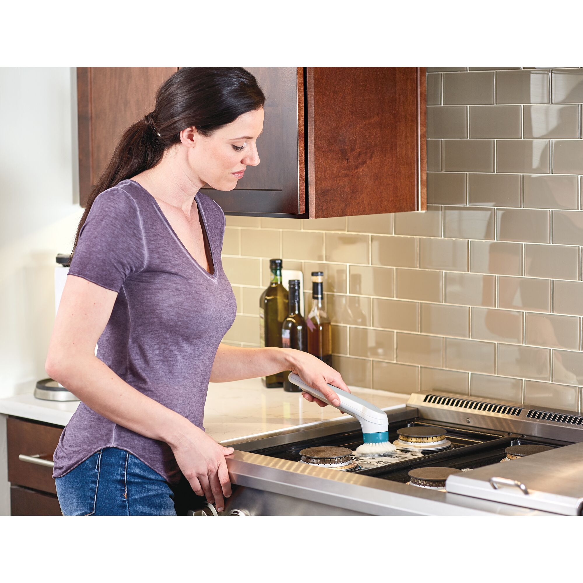 Photo of BLACKDECKER BHPC110 handheld power scrubber cleaning a stove top in a modern kitchen.