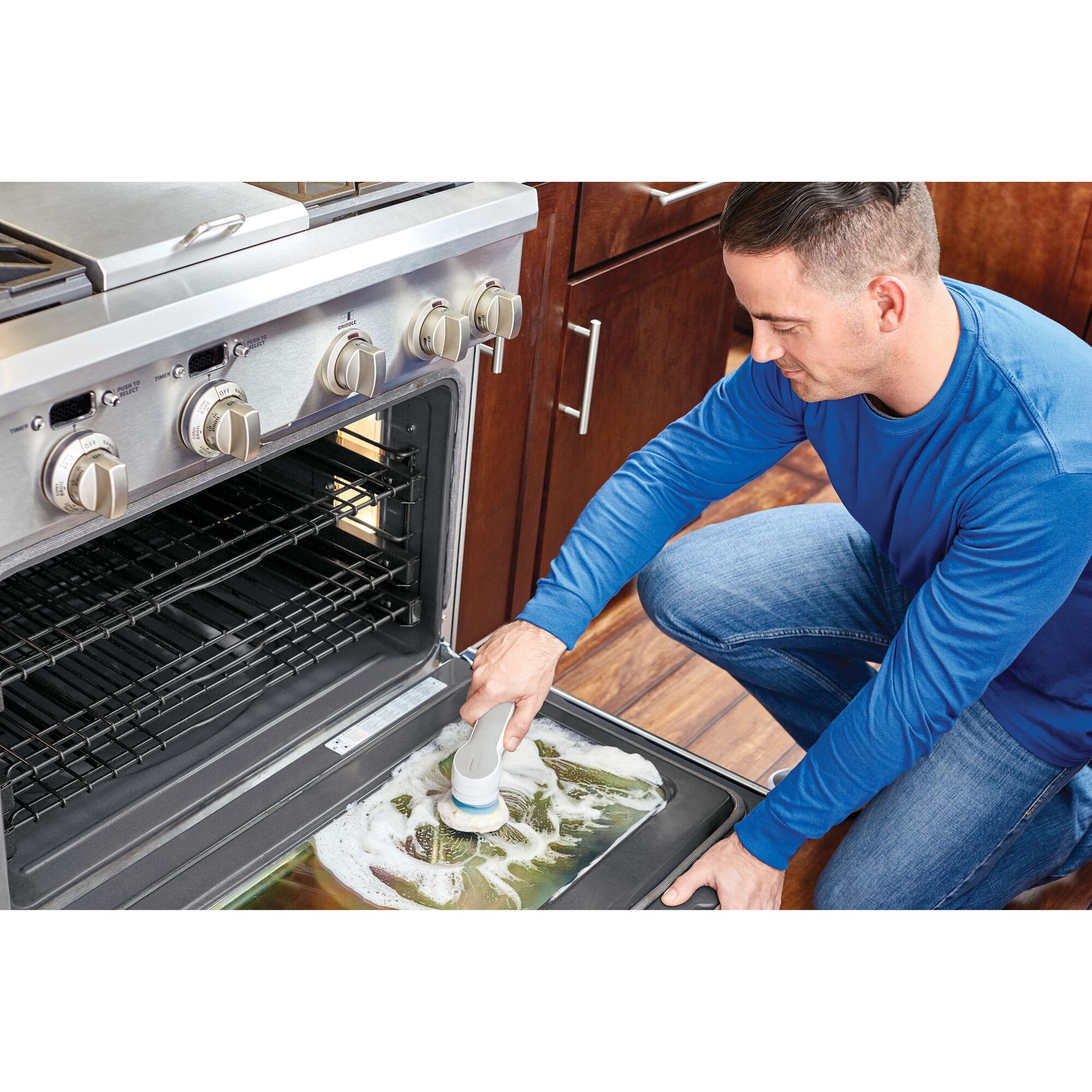 BLACKDECKER BHPC110 handheld scrubber cleaning oven door with soap, kitchen setting.