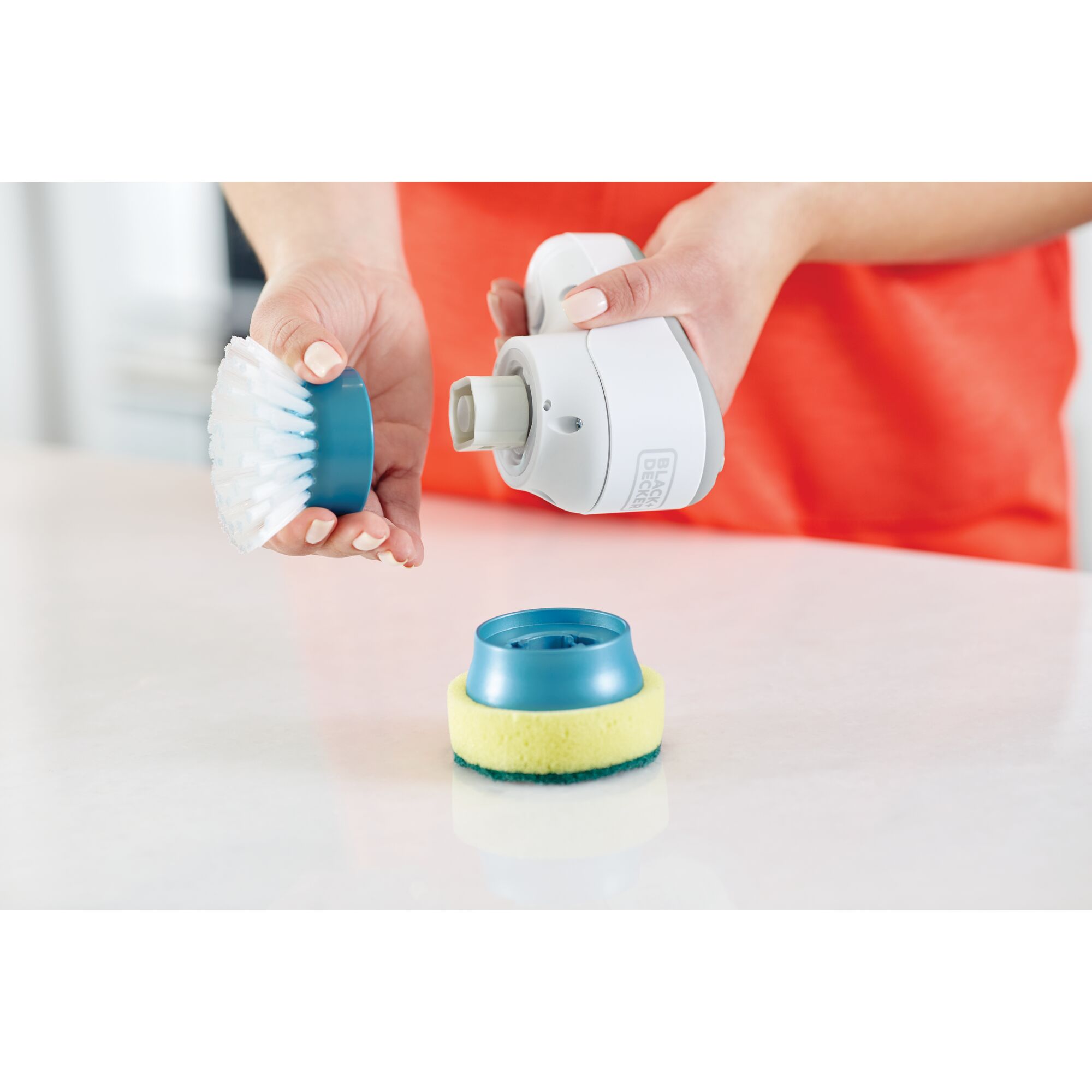 BLACKDECKER BHPC130 handheld scrubber with brush and sponge attachments on a countertop, side angle.
