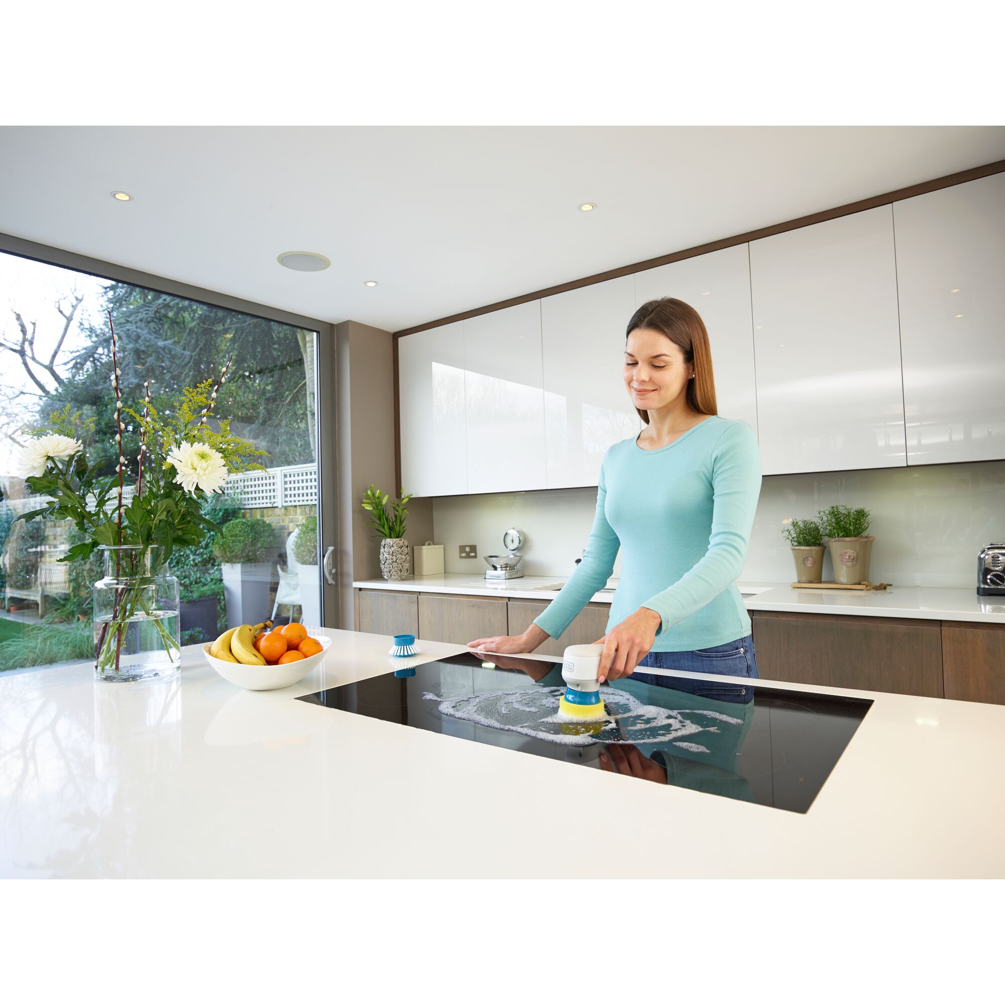 BLACKDECKER BHPC130 handheld scrubber cleaning a kitchen cooktop, modern kitchen setting.