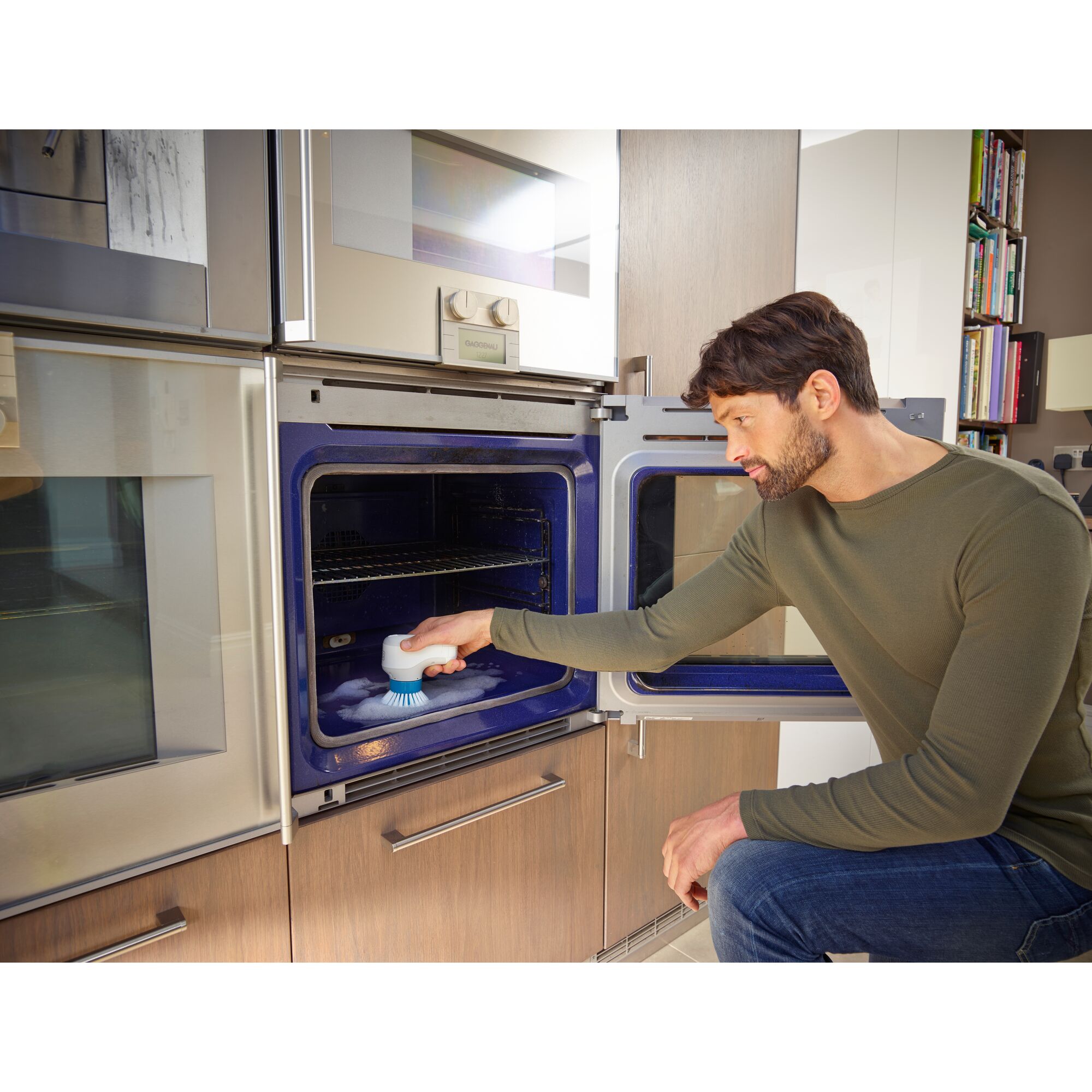 Photo of BLACKDECKER BHPC130 handheld scrub brush cleaning oven interior in kitchen setting.