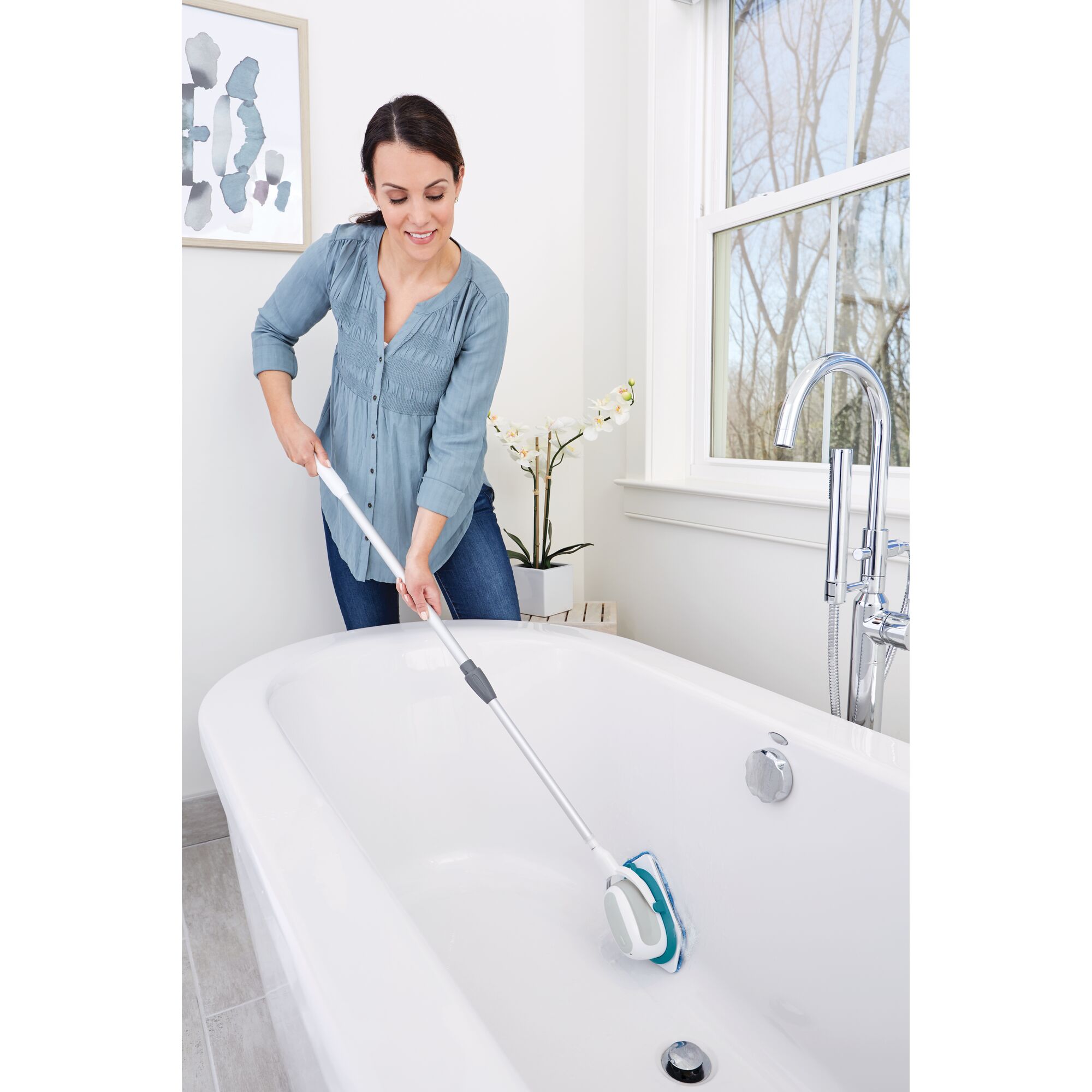 BLACKDECKER BHPC220 scrubber used to clean bathtub surface in bathroom, angled view.