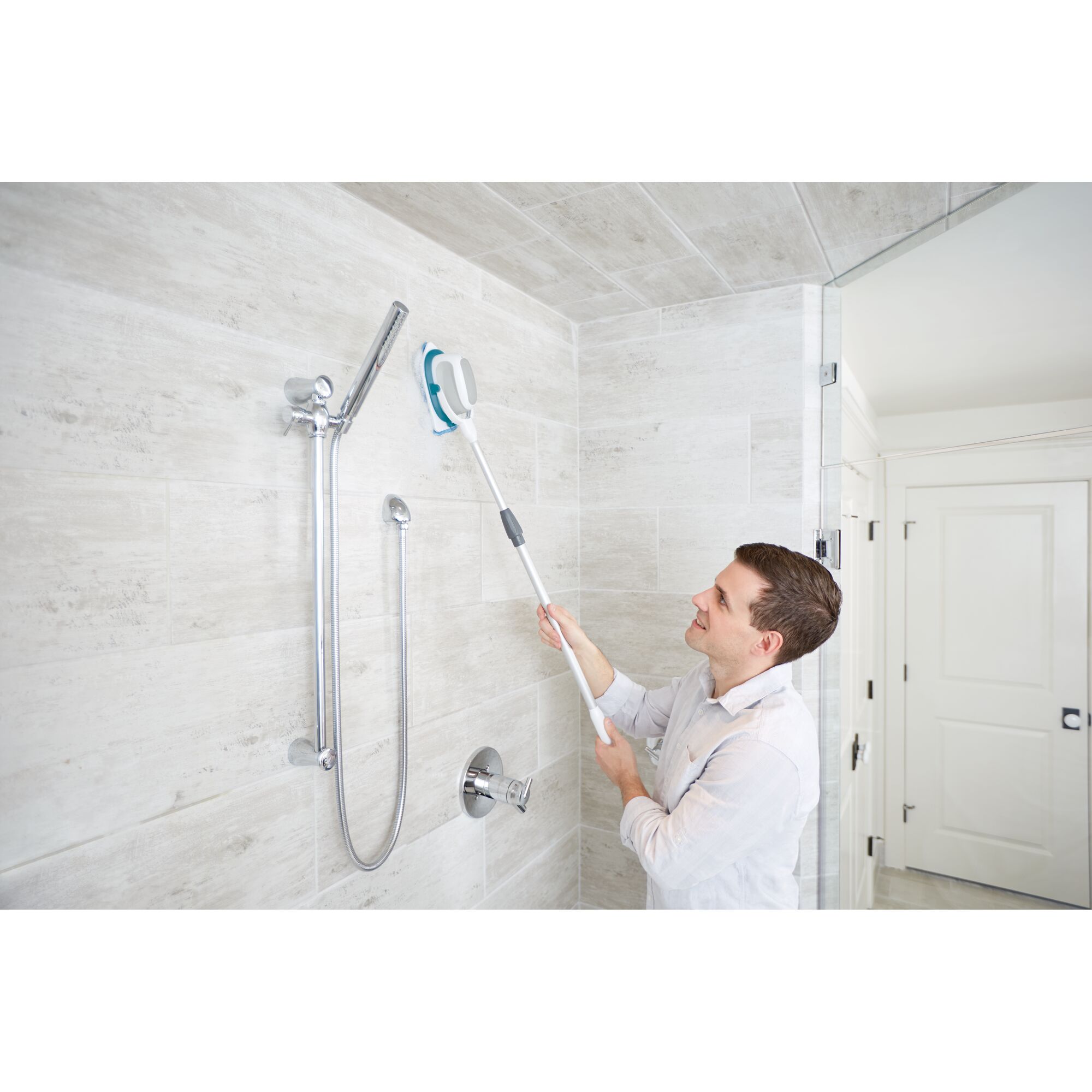 Photo of BLACKDECKER BHPC220 power scrubber cleaning shower wall with long handle attachment.