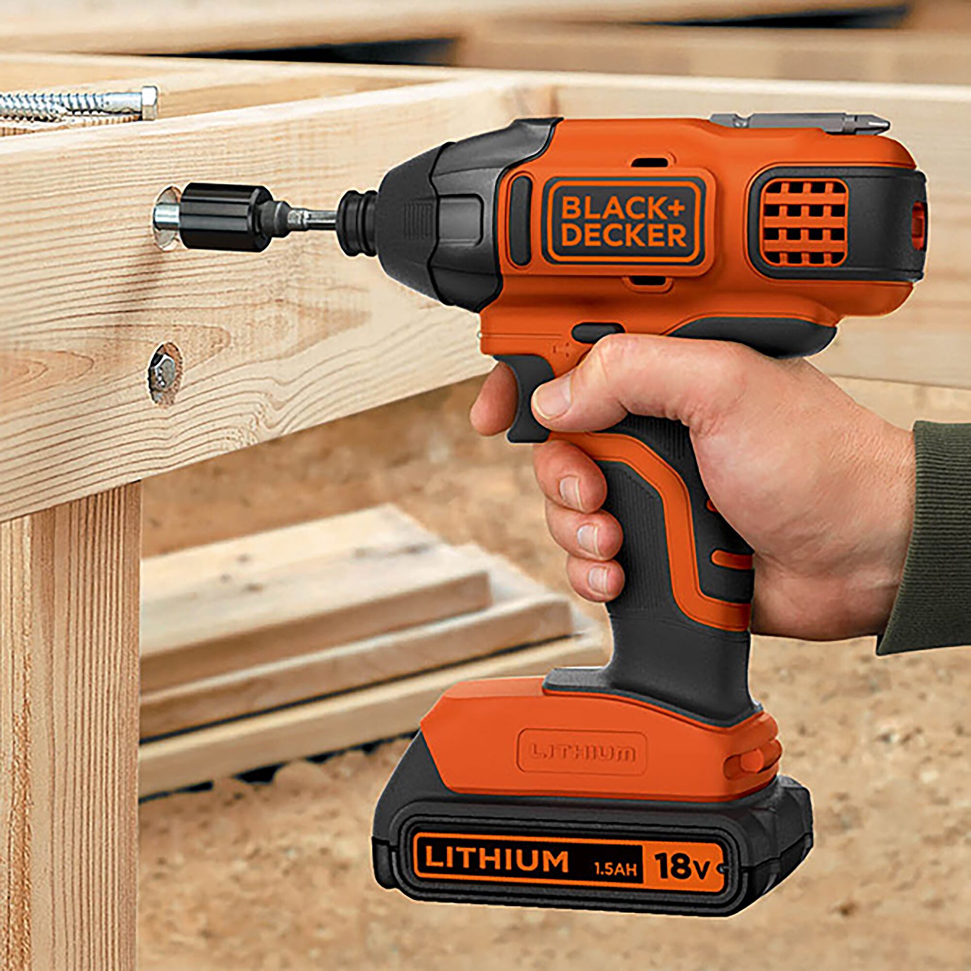 BLACK+DECKER BPCI18K1 cordless impact driver used on wooden beams, orange and black with 18V lithium battery.