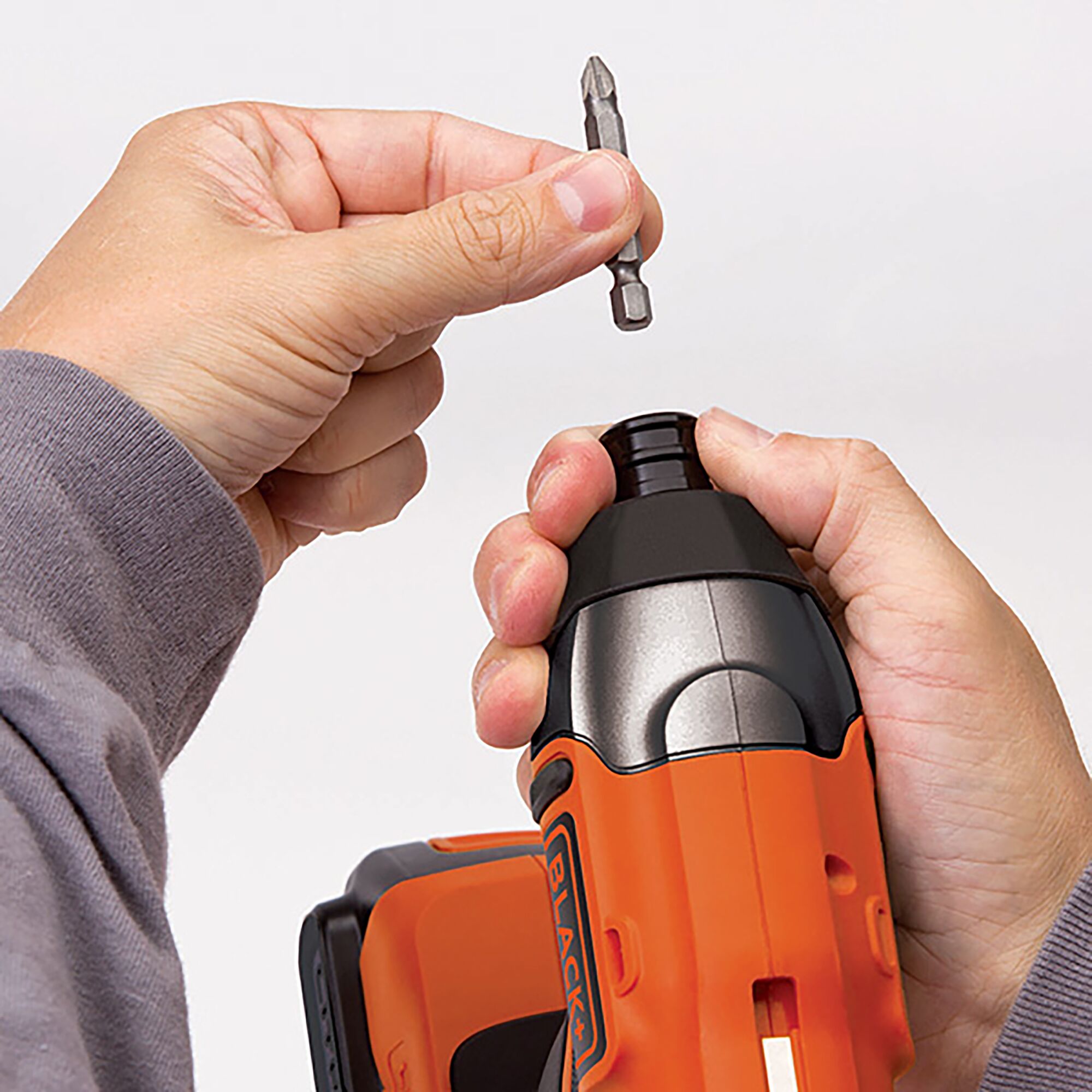 Photo of BLACKDECKER BPCI18K1 cordless drill in orange, with a hand inserting a bit into the chuck.