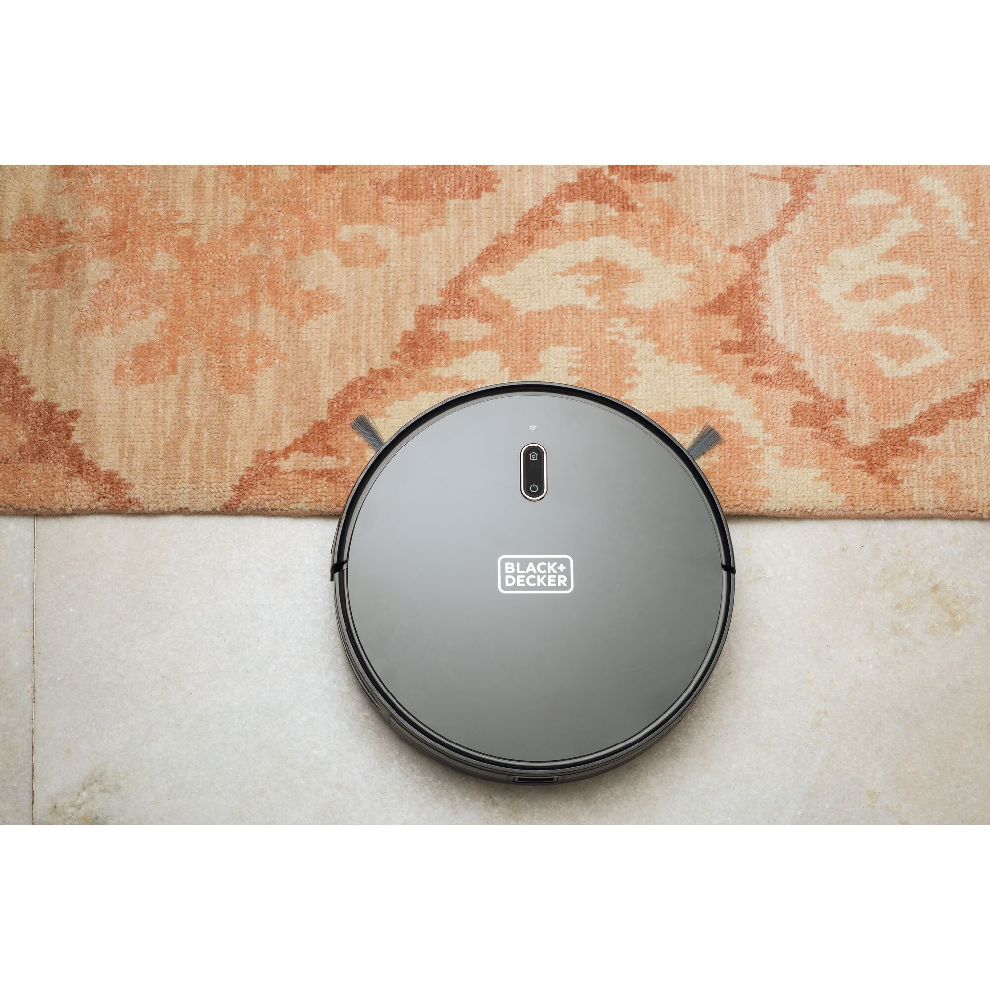 BLACK+DECKER BRVA425B00 robotic vacuum on tile and patterned rug, top view.