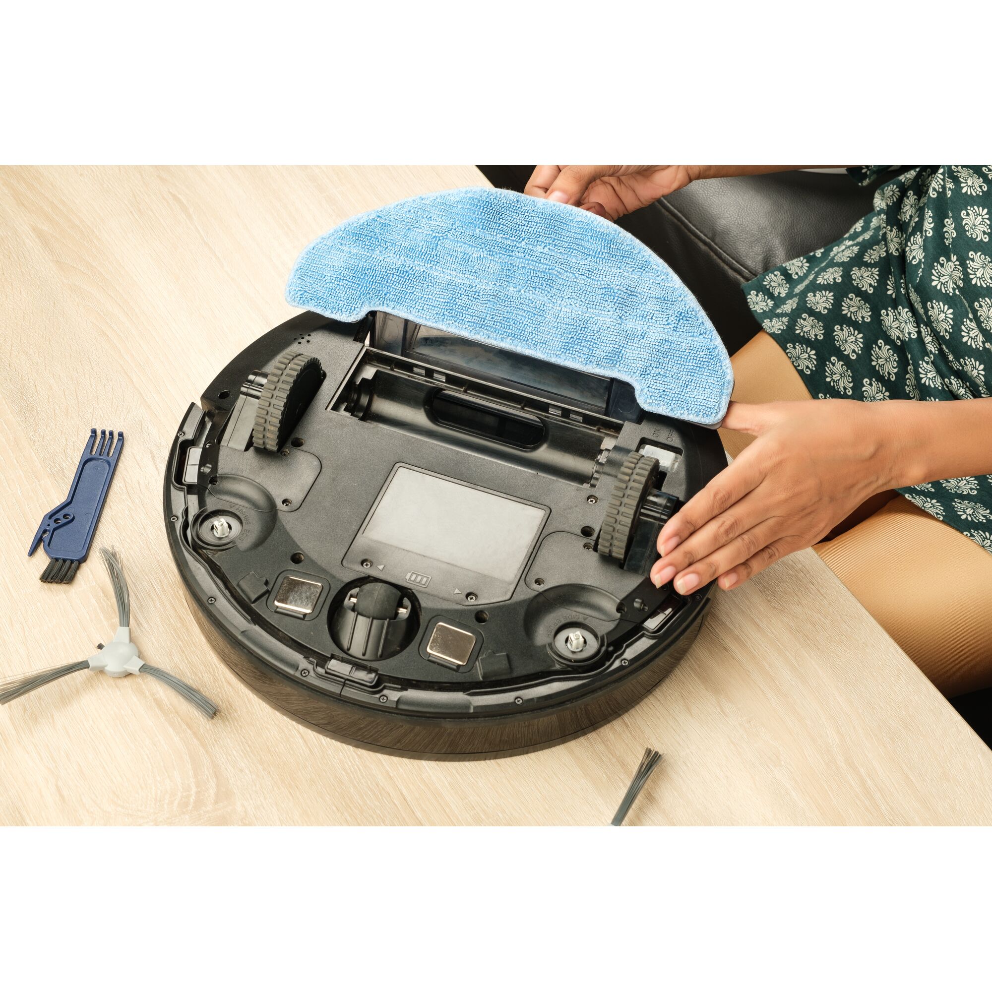 BLACKDECKER BRVA425B00 robot vacuum underside with blue cleaning pad and tools on table.