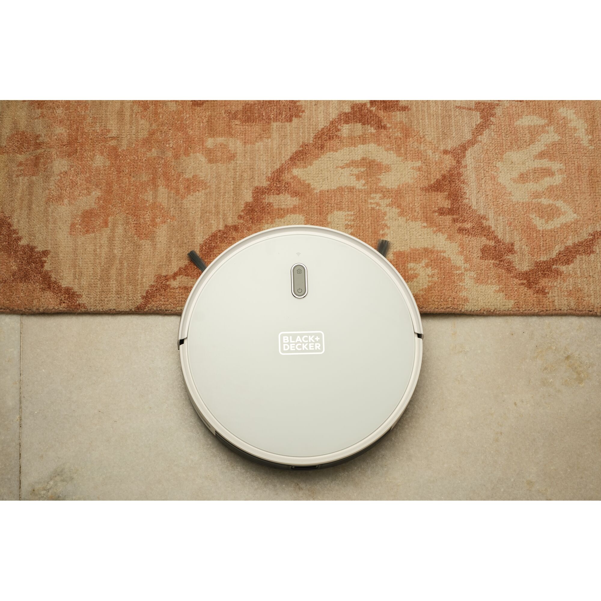 BLACKDECKER BRVA425B10 robot vacuum cleaner on patterned rug and tile, top view.