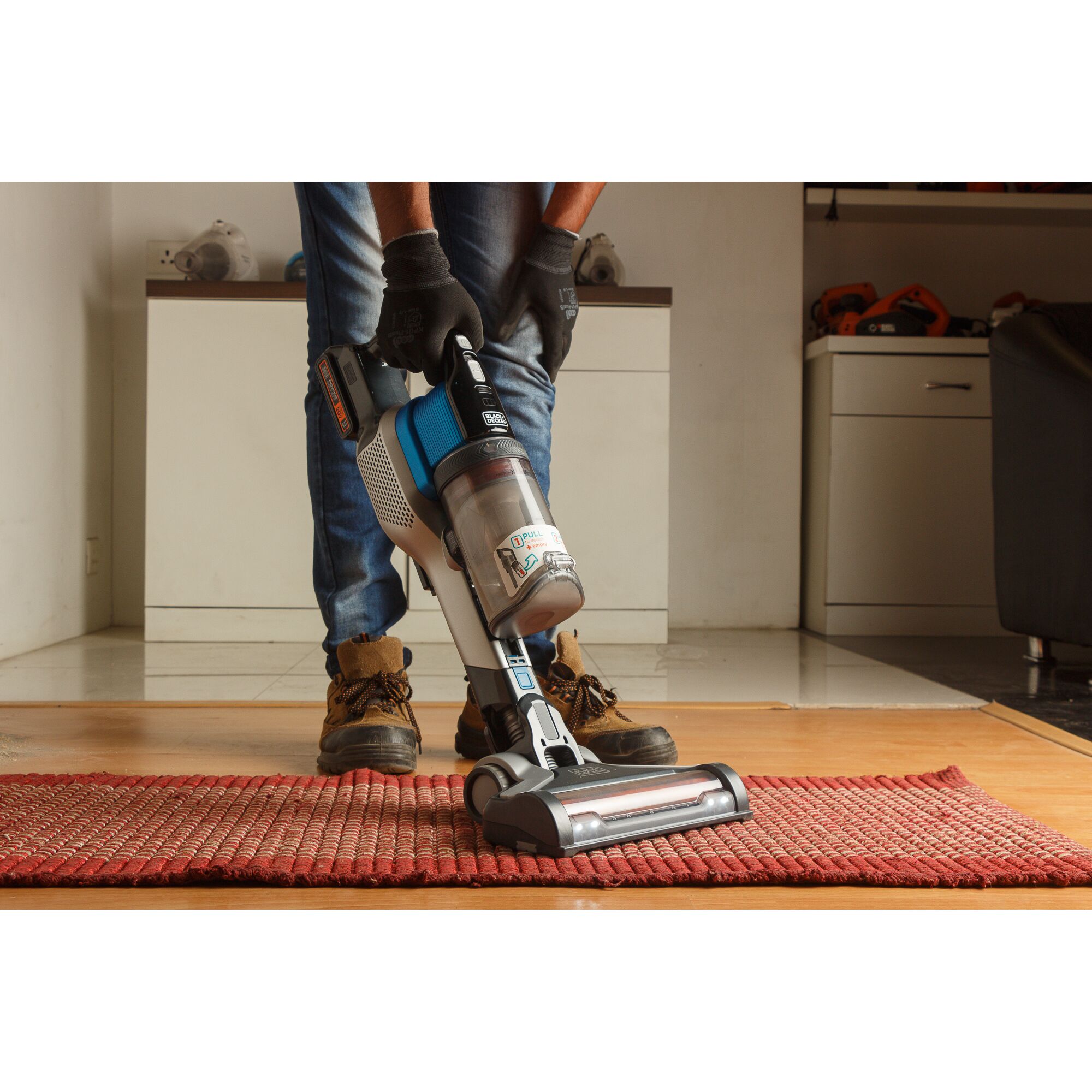 BLACKDECKER BSV2020G cordless stick vacuum cleaning a red rug in a home setting.