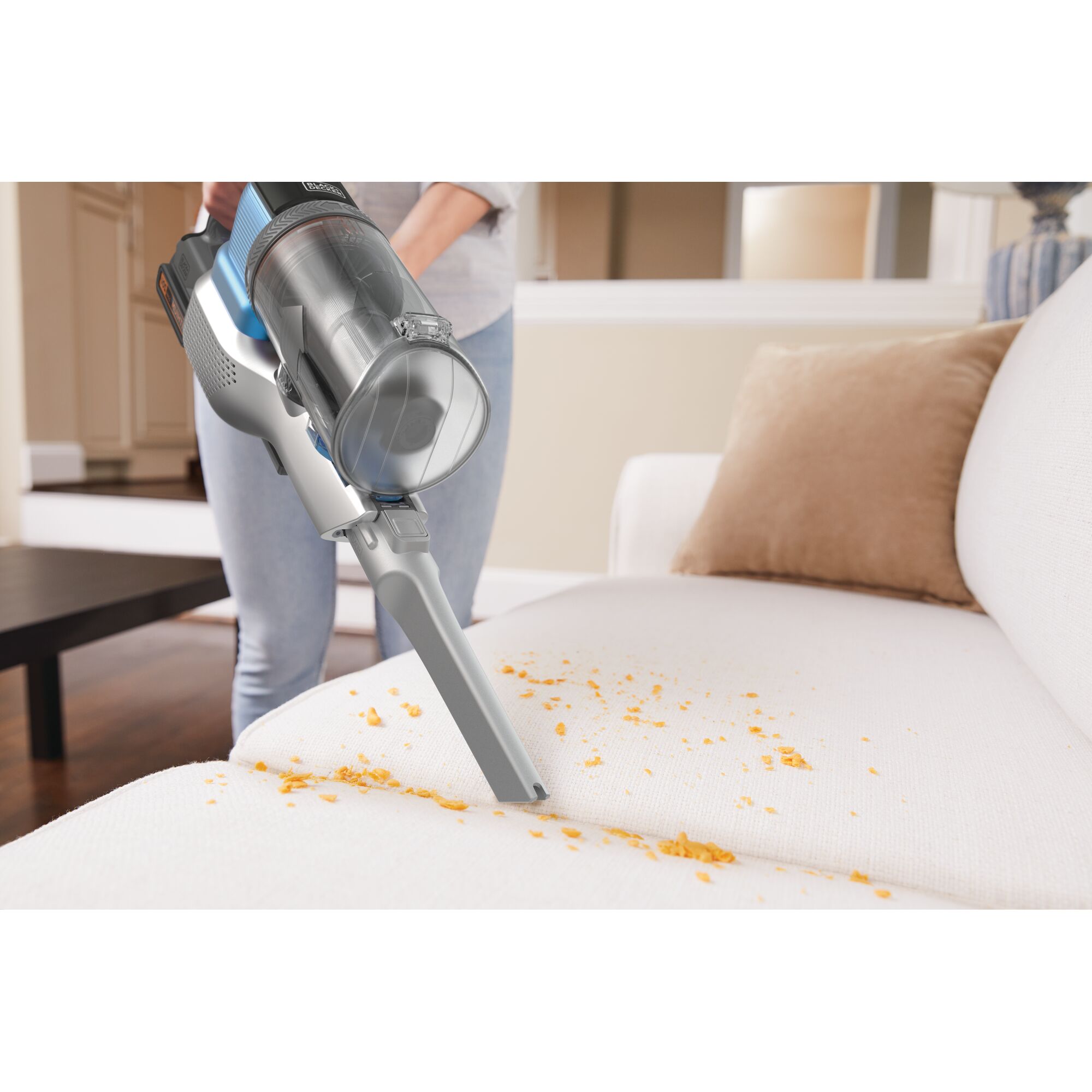 BLACKDECKER BSV2020G handheld vacuum cleaning crumbs on white sofa, close-up view.