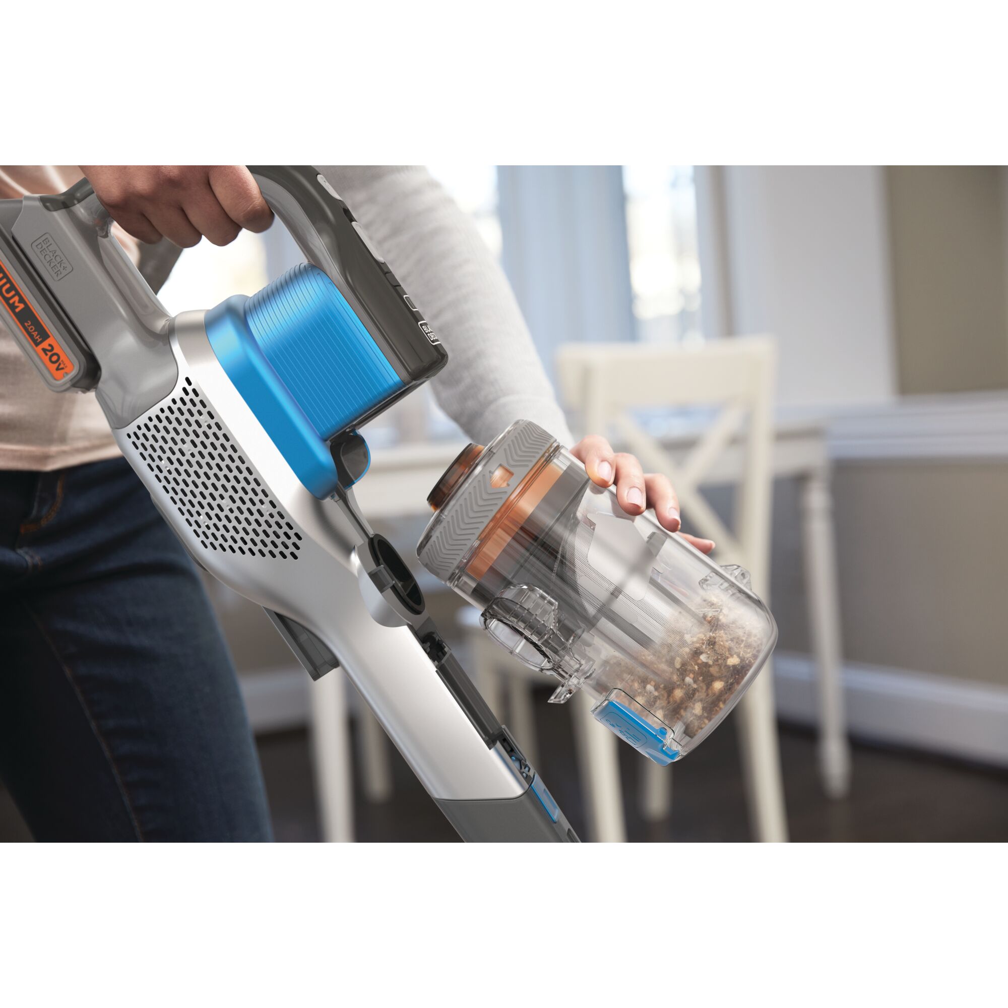 BLACKDECKER BSV2020G cordless stick vacuum with blue and gray body, dustbin being emptied indoors.