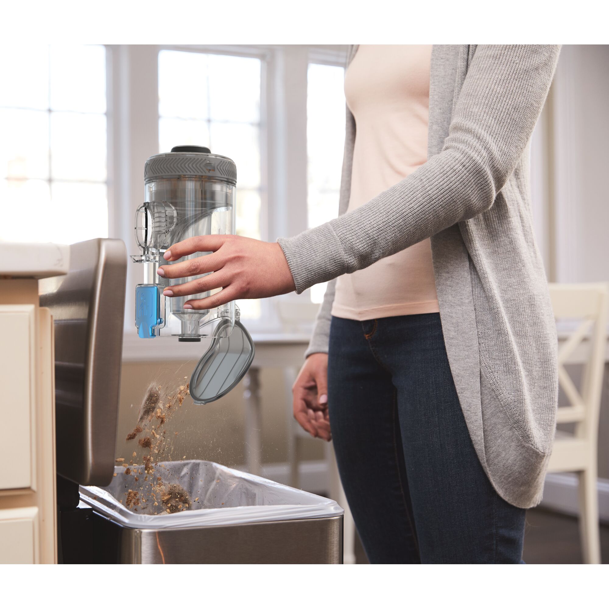 BLACKDECKER BSV2020G vacuum canister being emptied into kitchen trash bin.
