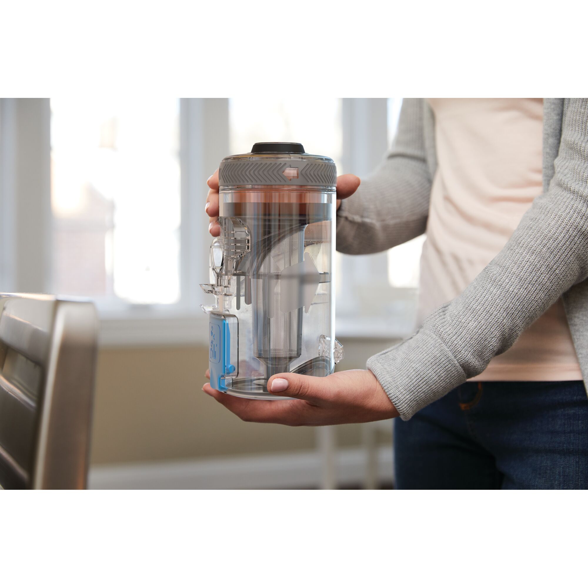 Photo of BLACKDECKER BSV2020G clear dustbin canister for vacuum, held by person indoors.