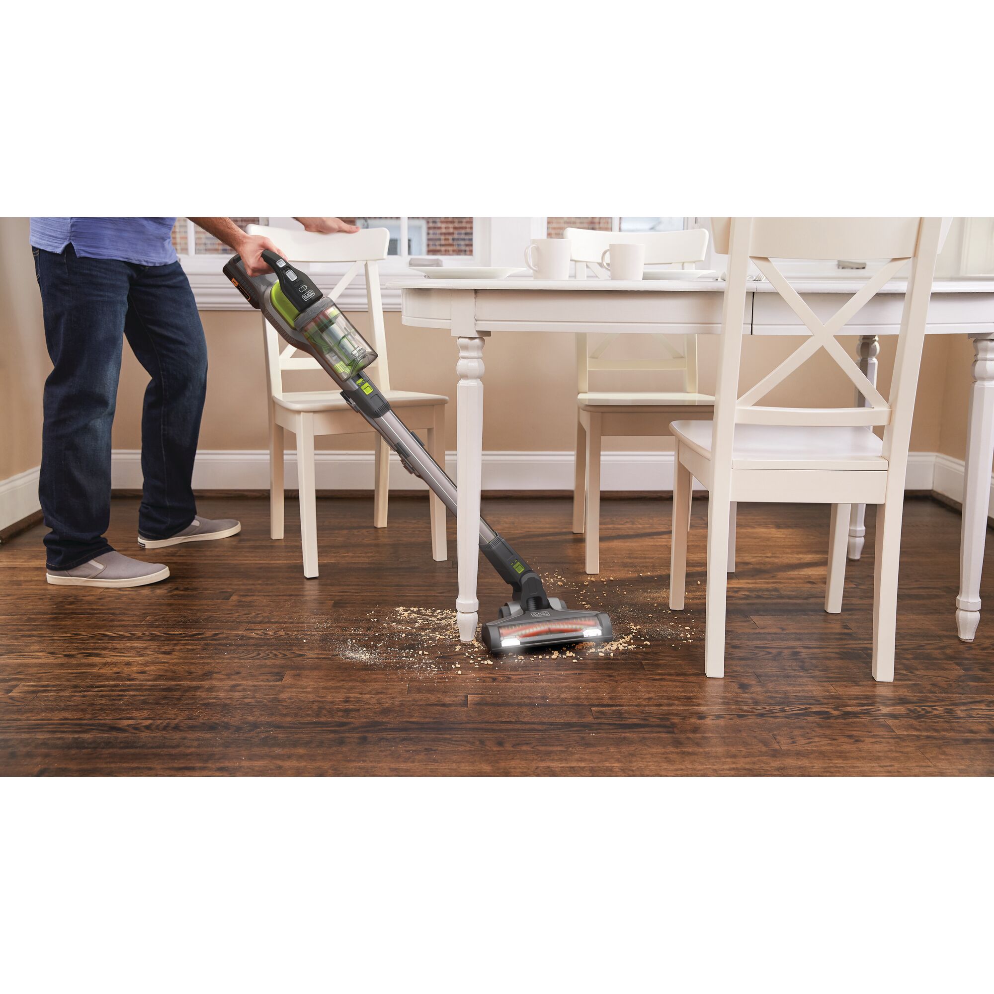 BLACKDECKER BSV4020AS cordless stick vacuum cleaning wooden floor under table with visible debris.