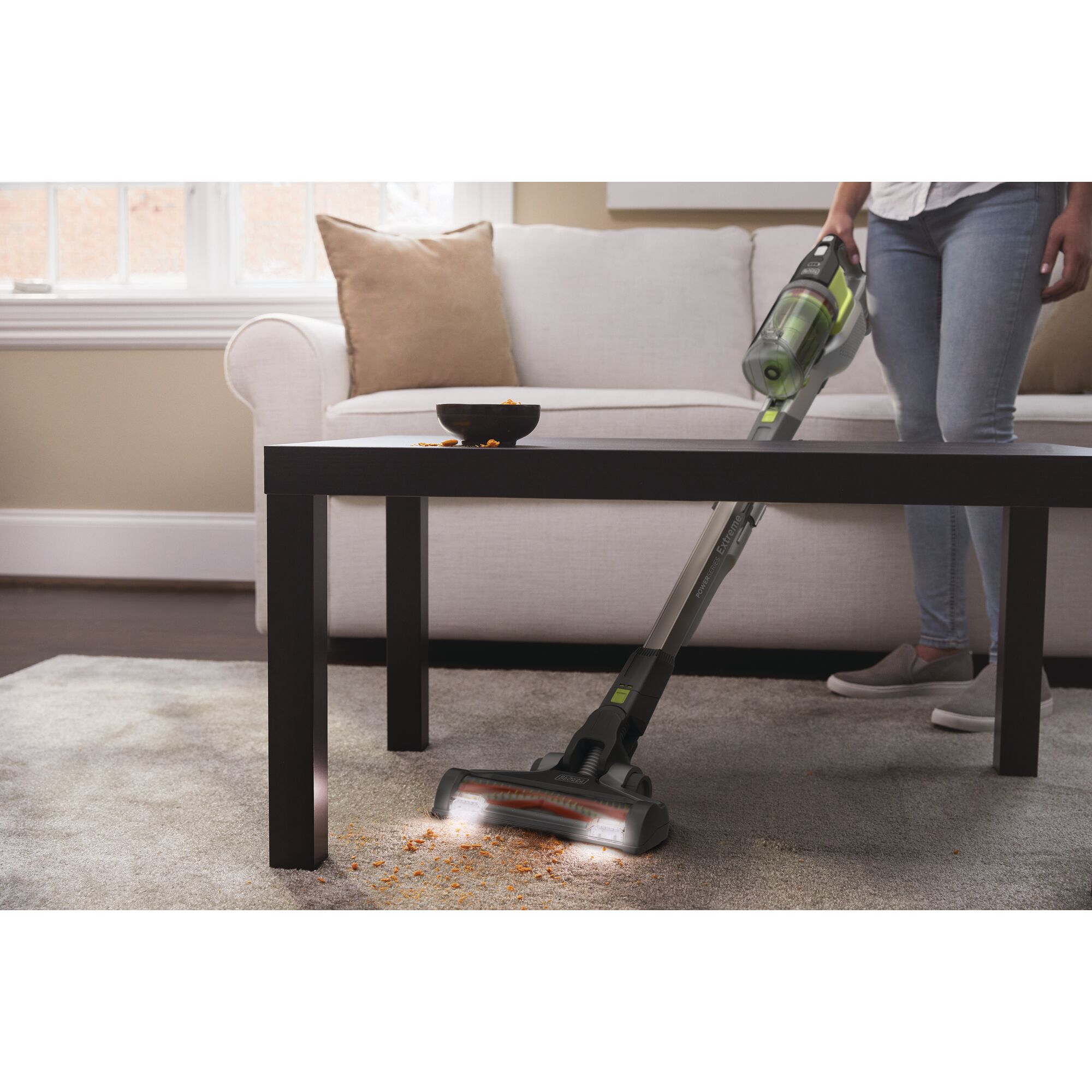 BLACKDECKER BSV4020AS cordless stick vacuum cleaning crumbs on carpet in living room, side view.
