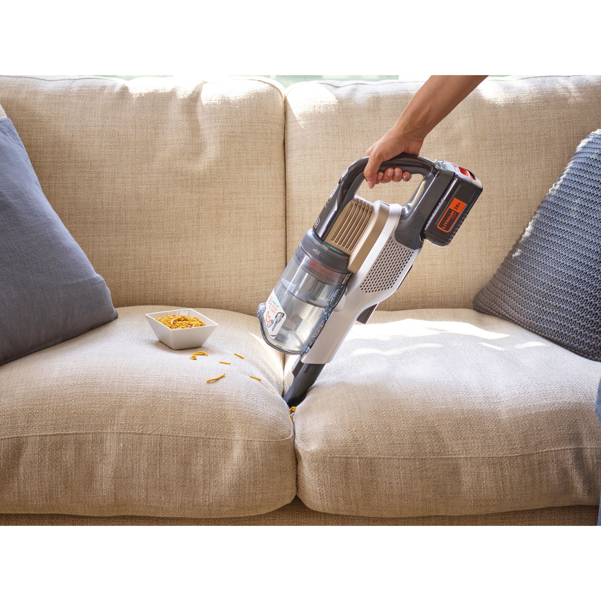 BLACKDECKER BSV4020RBLS cordless vacuum cleaning crumbs from beige sofa, side angle.