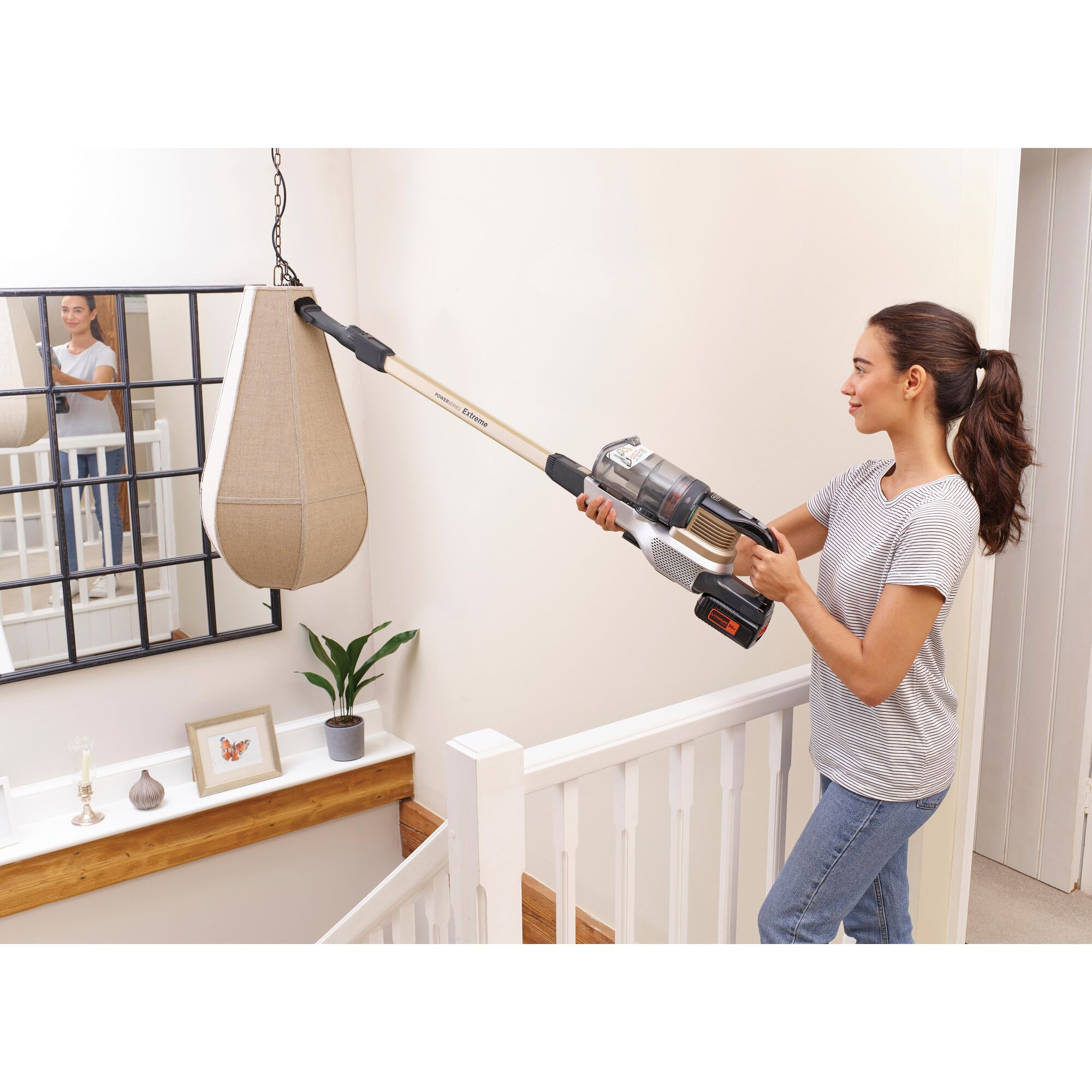 BLACKDECKER BSV4020RBLS cordless stick vacuum with extension wand cleaning a hanging lamp in a stairwell.