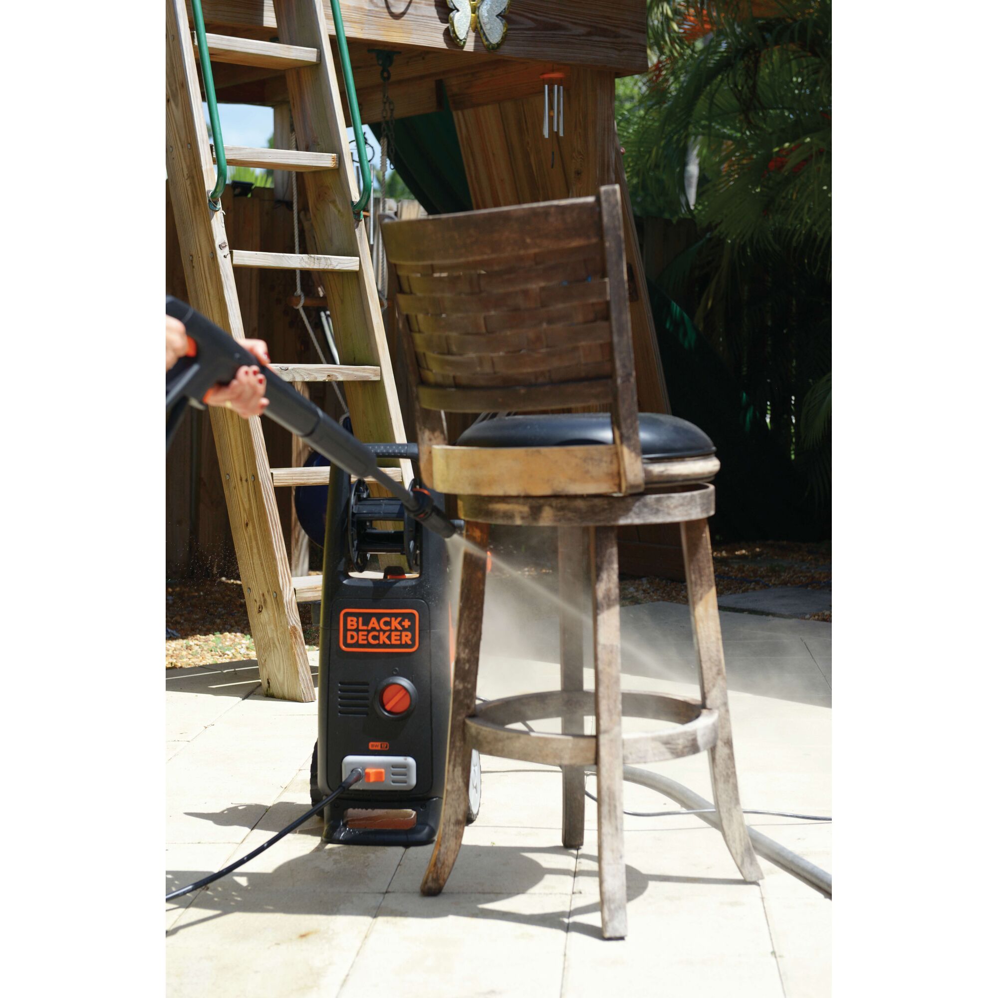 BLACKDECKER BW17 pressure washer cleaning a wooden chair outdoors, product in use.