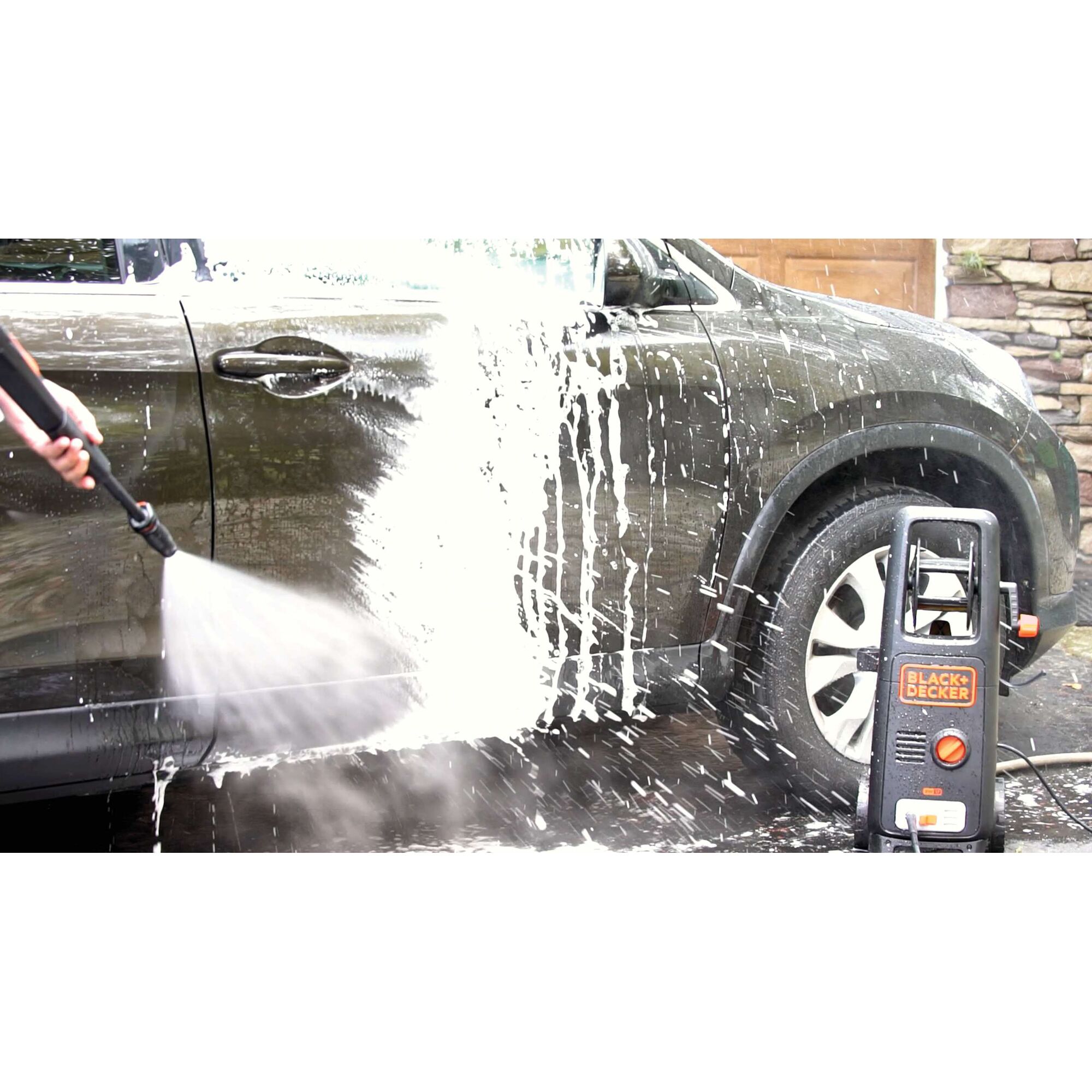 BLACKDECKER BW17 pressure washer spraying foam on a car side during outdoor washing.
