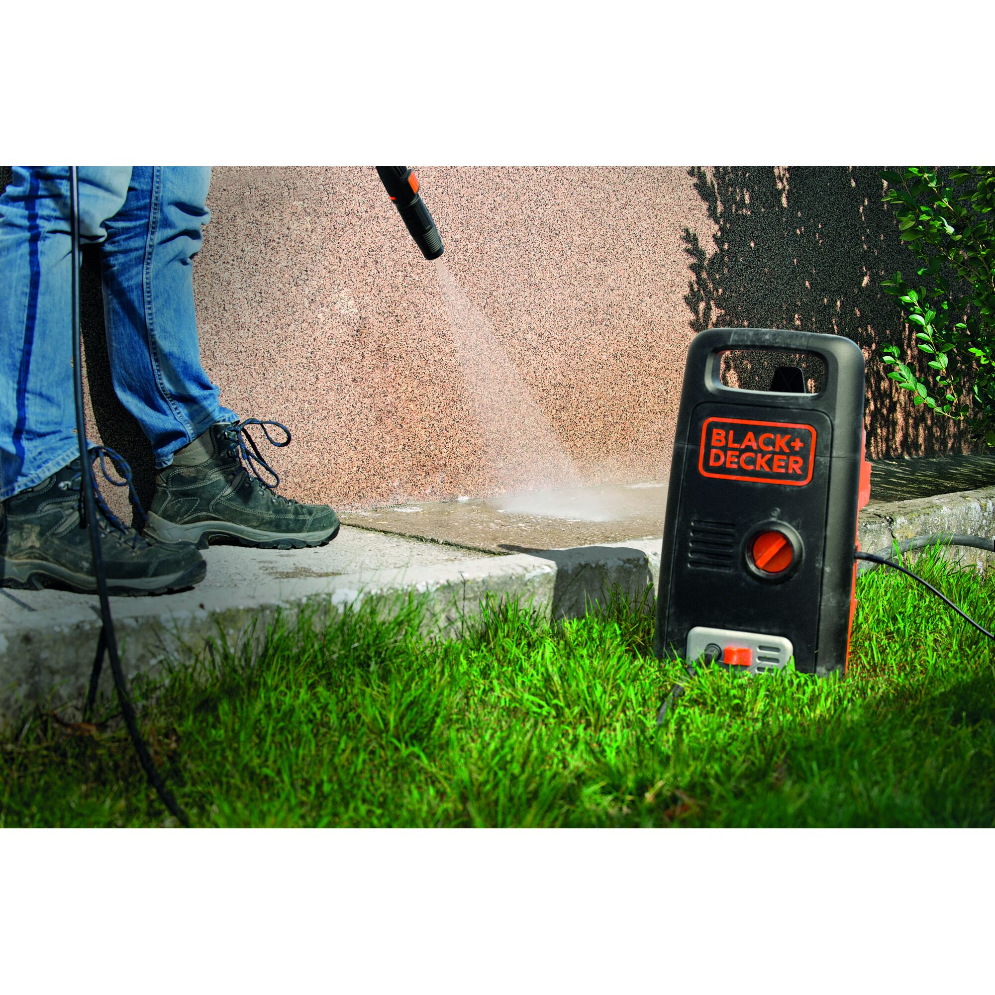 BLACK+DECKER BXPW1300E pressure washer cleaning concrete outdoors, person holding spray wand.