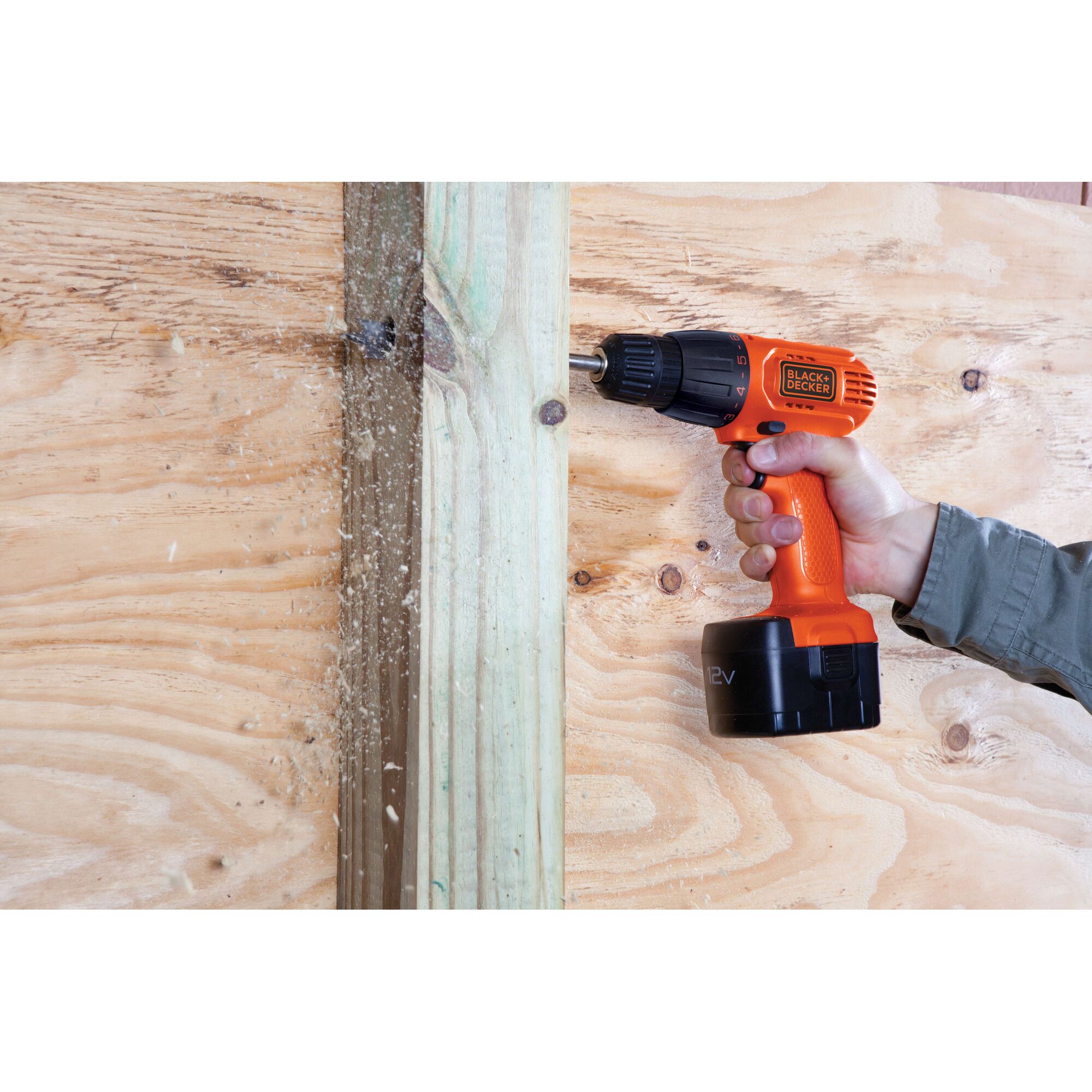 Photo of BLACKDECKER CD121K50 cordless drill in use on wood surface, hand holding the orange power tool.