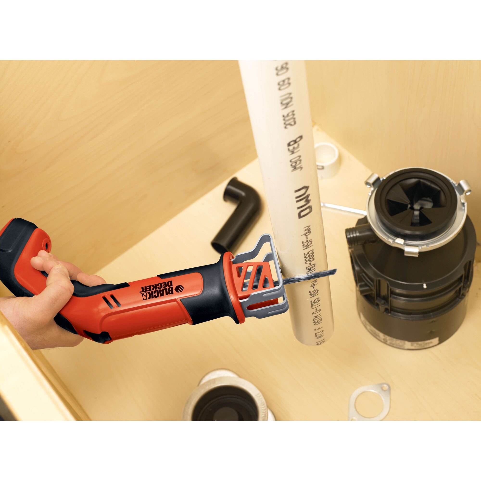 BLACKDECKER CHS6000 cordless reciprocating saw cutting PVC pipe under sink, close-up side angle.
