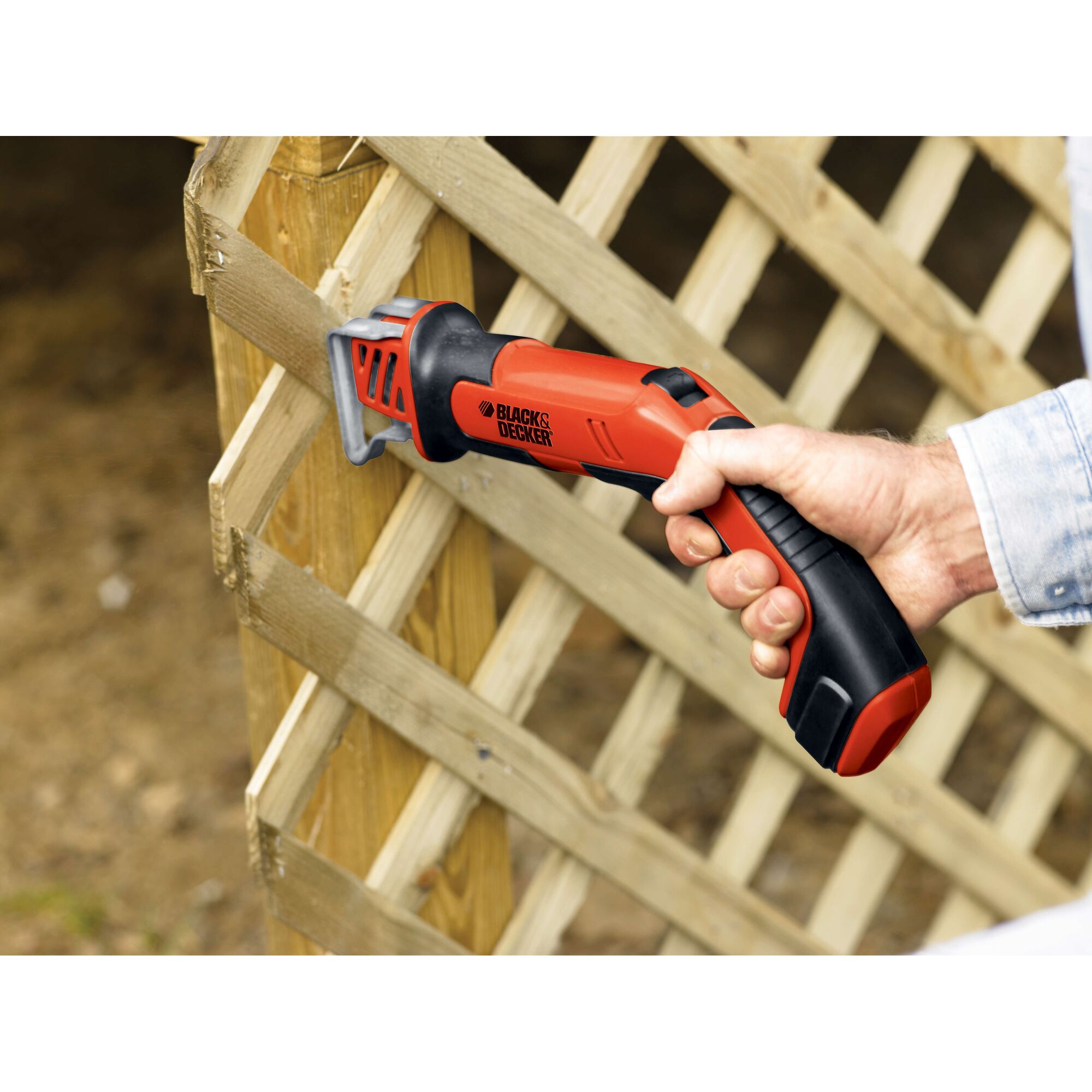 BLACKDECKER CHS6000 cordless reciprocating saw in use cutting wooden lattice outdoors.