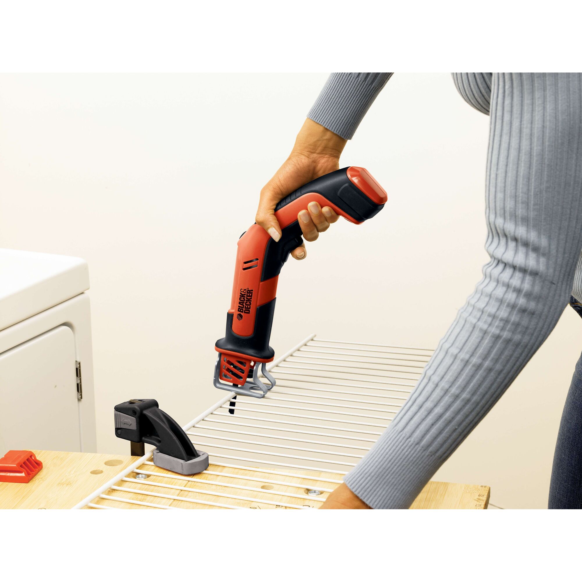 Photo of BLACKDECKER CHS6000 cordless handheld saw cutting metal wire rack on workbench.