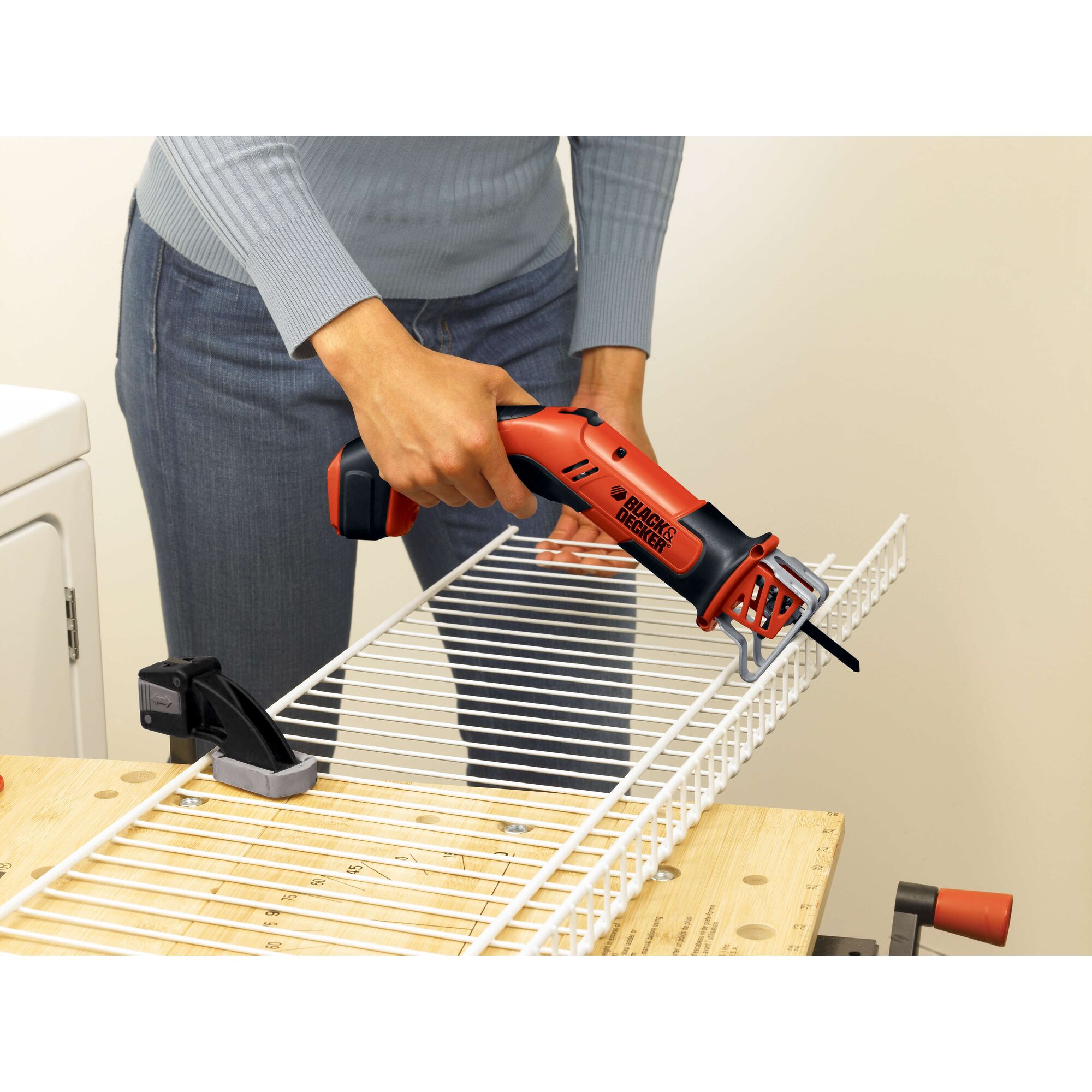 Photo of BLACKDECKER CHS6000 cordless reciprocating saw cutting a white wire shelf on a workbench.