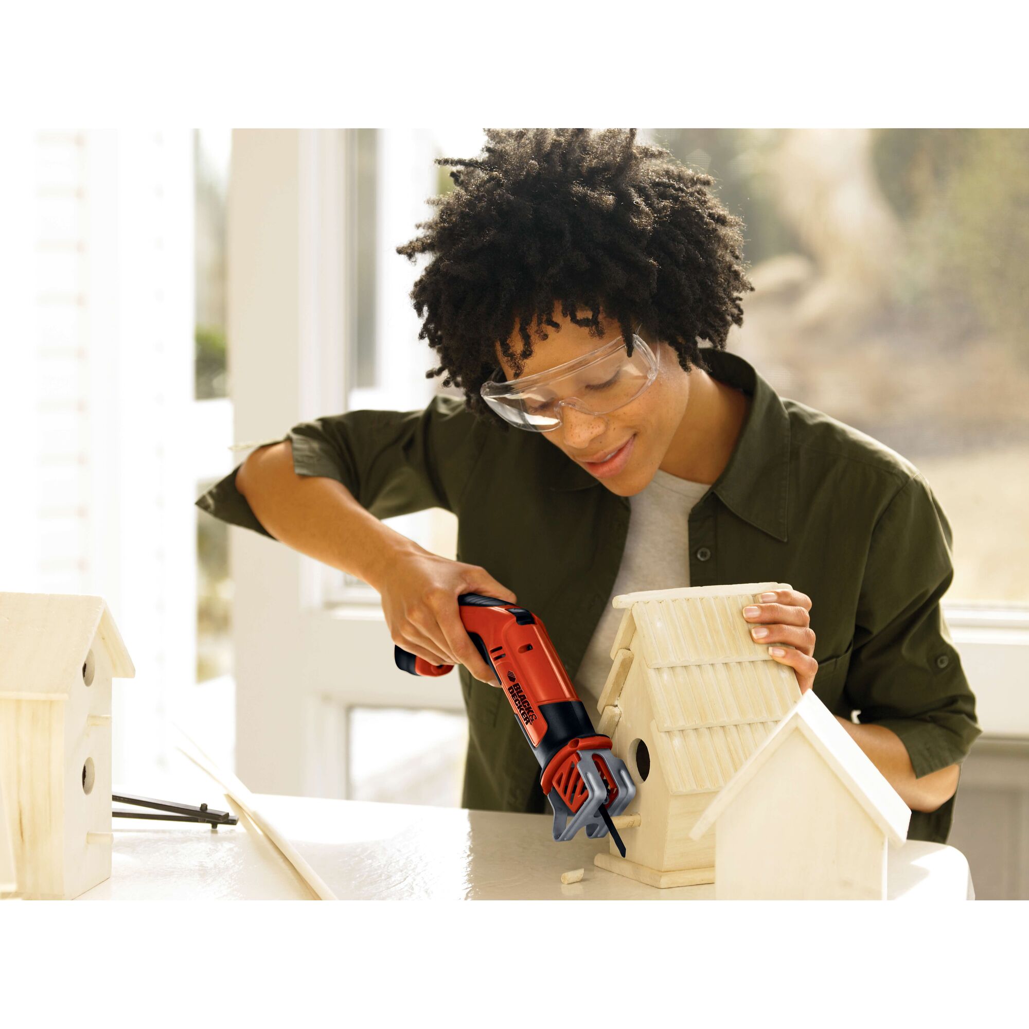 Photo of BLACKDECKER CHS6000 cordless saw used to cut wood birdhouse on white table.
