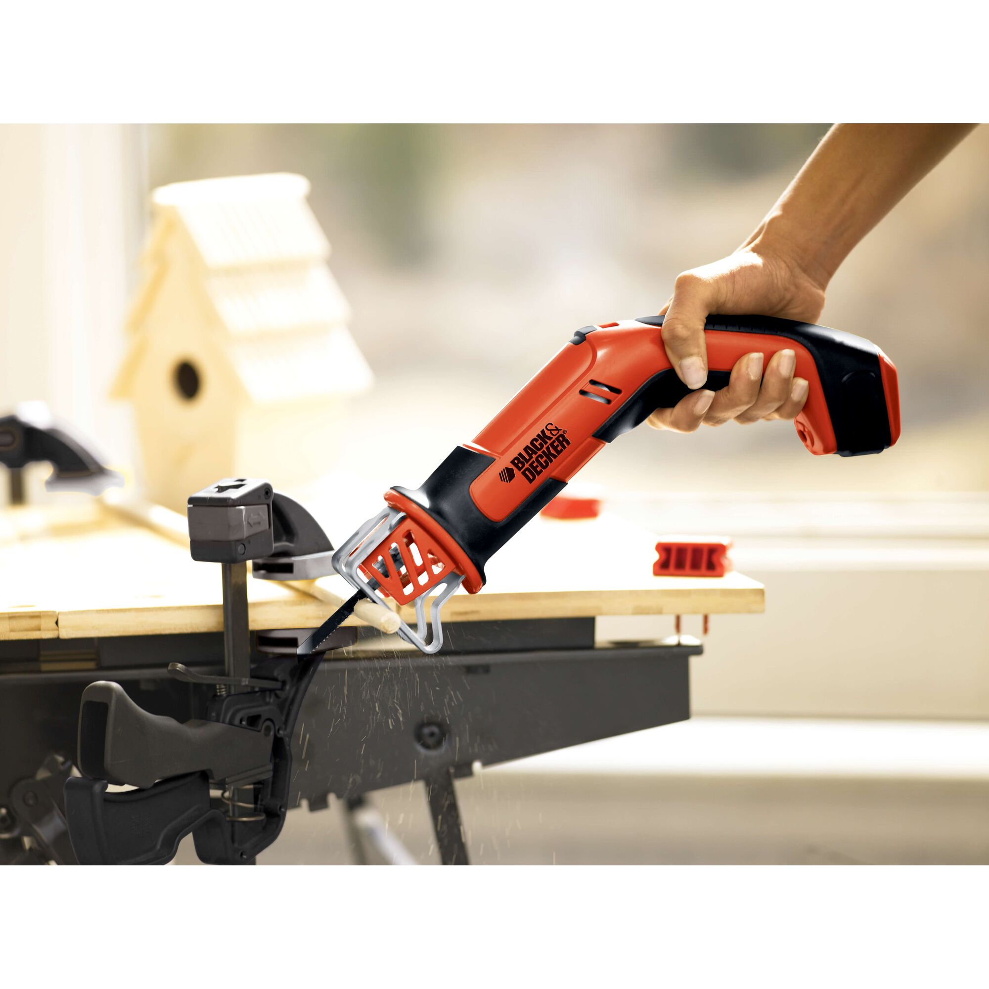 BLACKDECKER CHS6000 cordless reciprocating saw cutting wood on workbench, side angle.