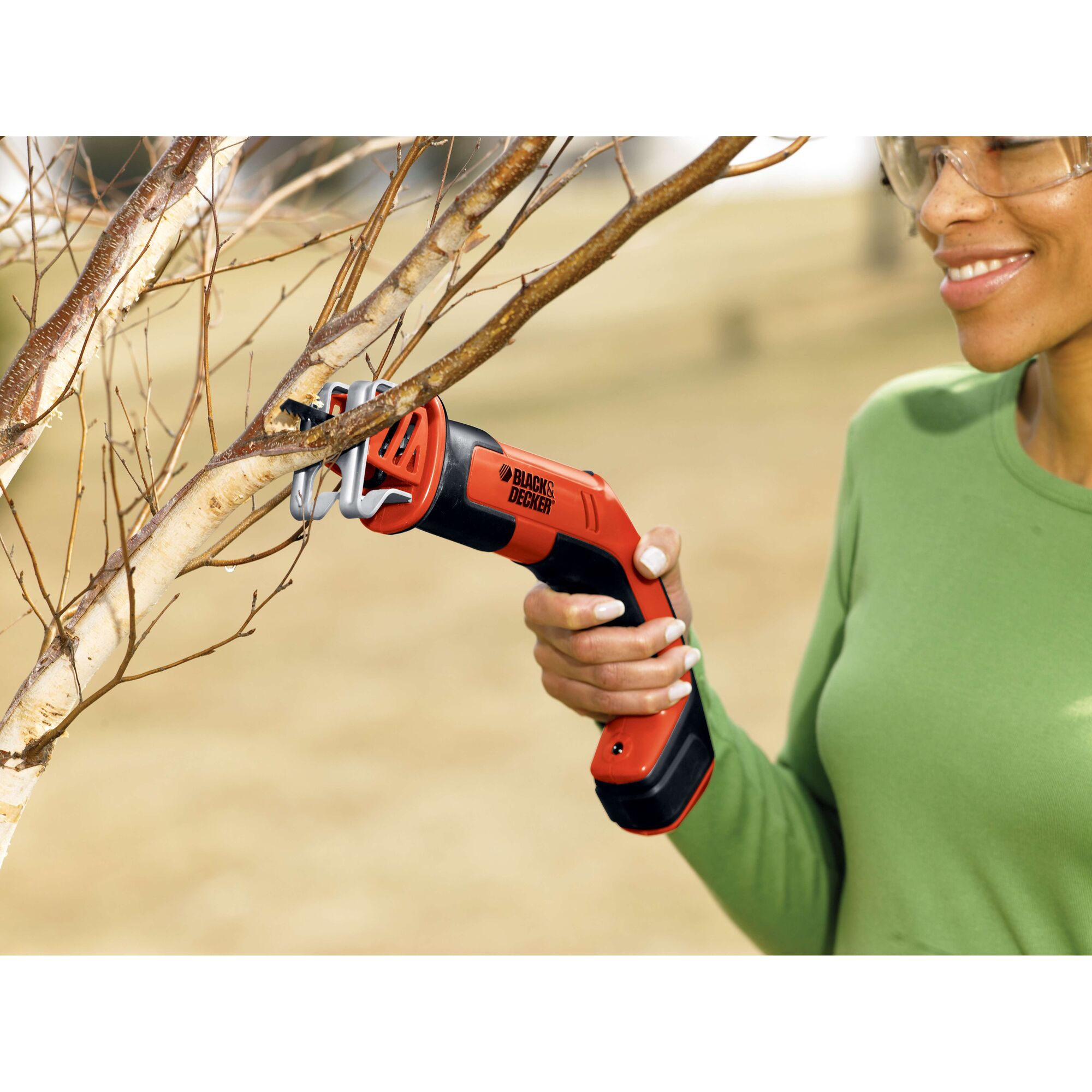 Photo of BLACKDECKER CHS6000 cordless handheld pruning saw trimming tree branches outdoors.