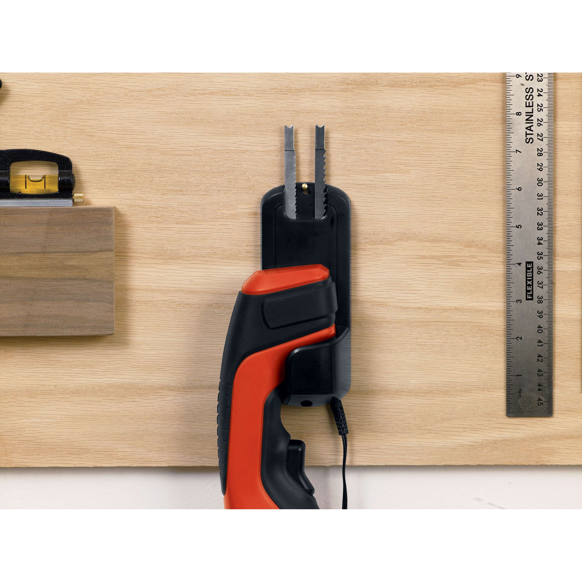 BLACKDECKER CHS6000 handheld electric saw in wall mount charger, side angle, red and black handle visible.