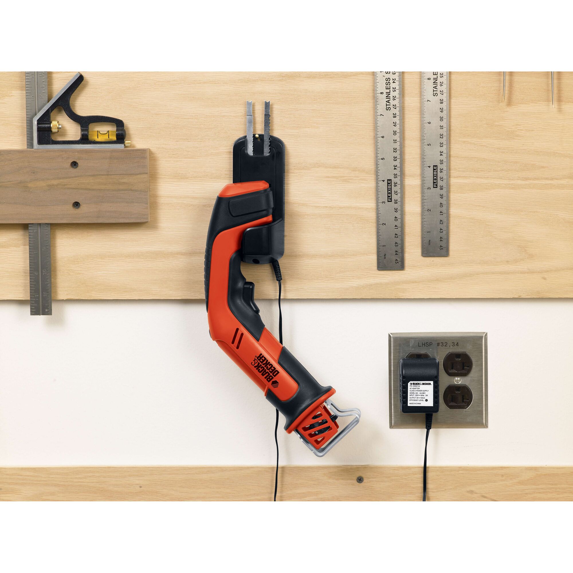 BLACKDECKER CHS6000 cordless saw in orange and black on wall charger in workshop setting.
