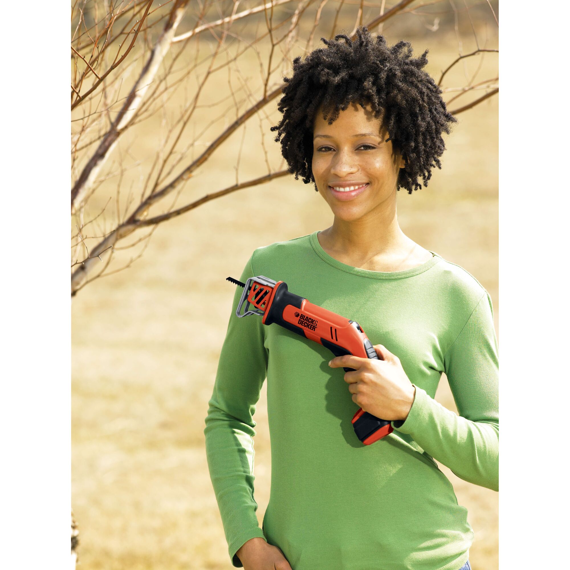 Photo of BLACKDECKER CHS6000 orange cordless saw held by person in green shirt outdoors.