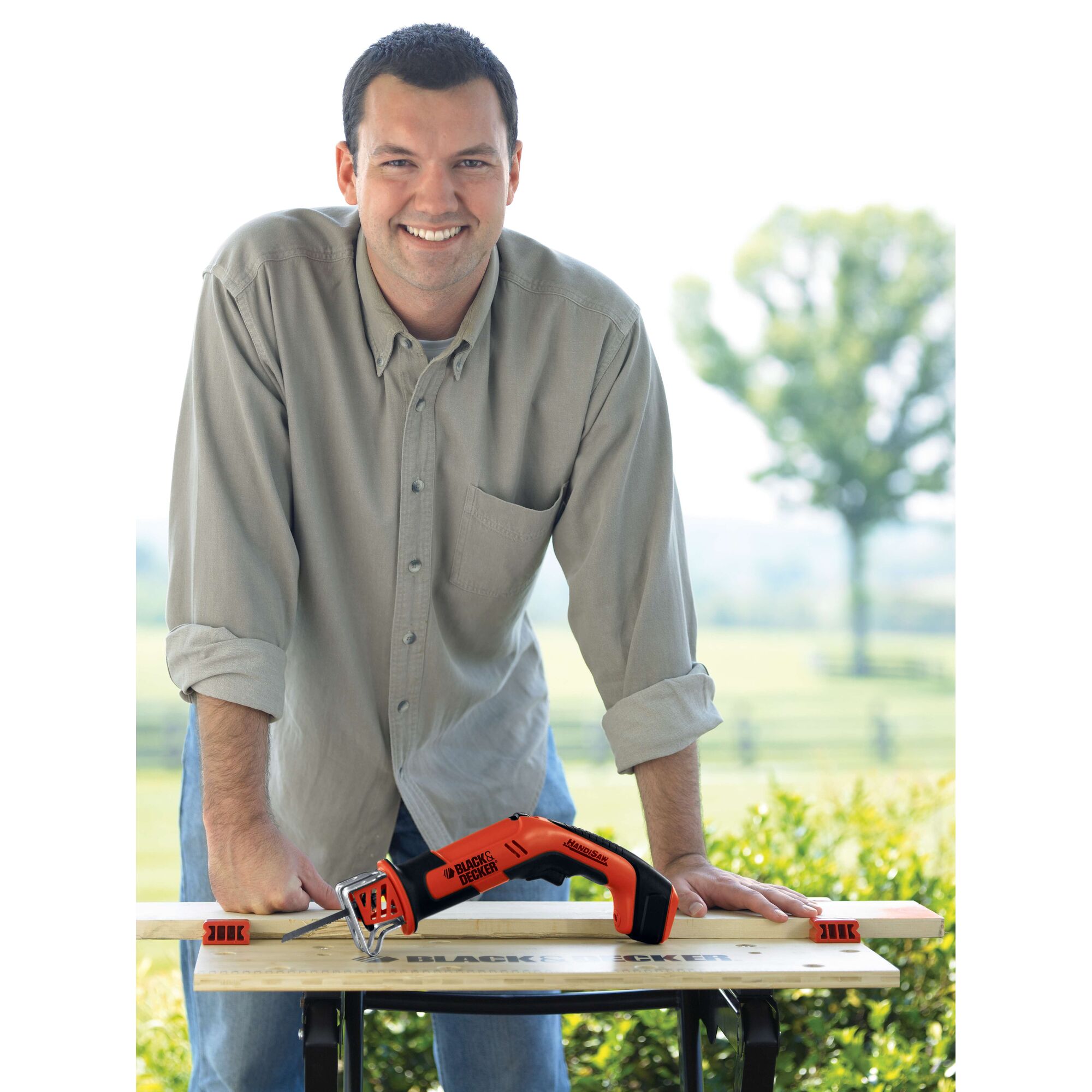 Photo of BLACKDECKER CHS6000 orange cordless saw being used on a wooden plank outdoors.