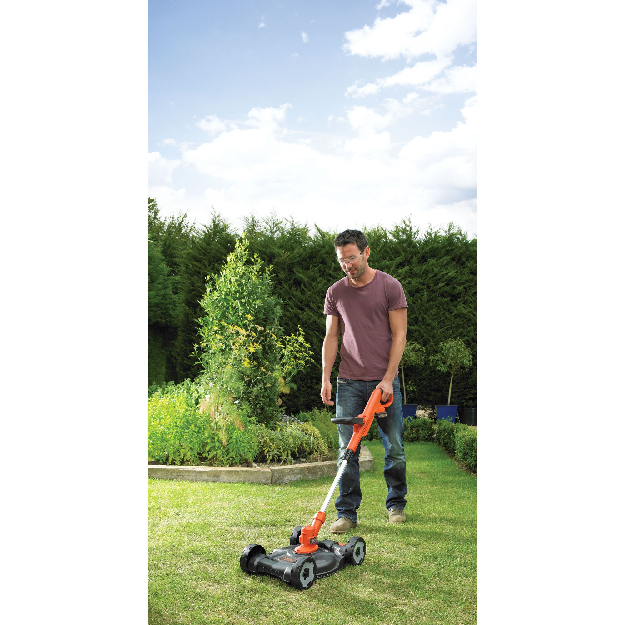 BLACKDECKER CM100N lawn mower with orange and black design being used in a garden setting.