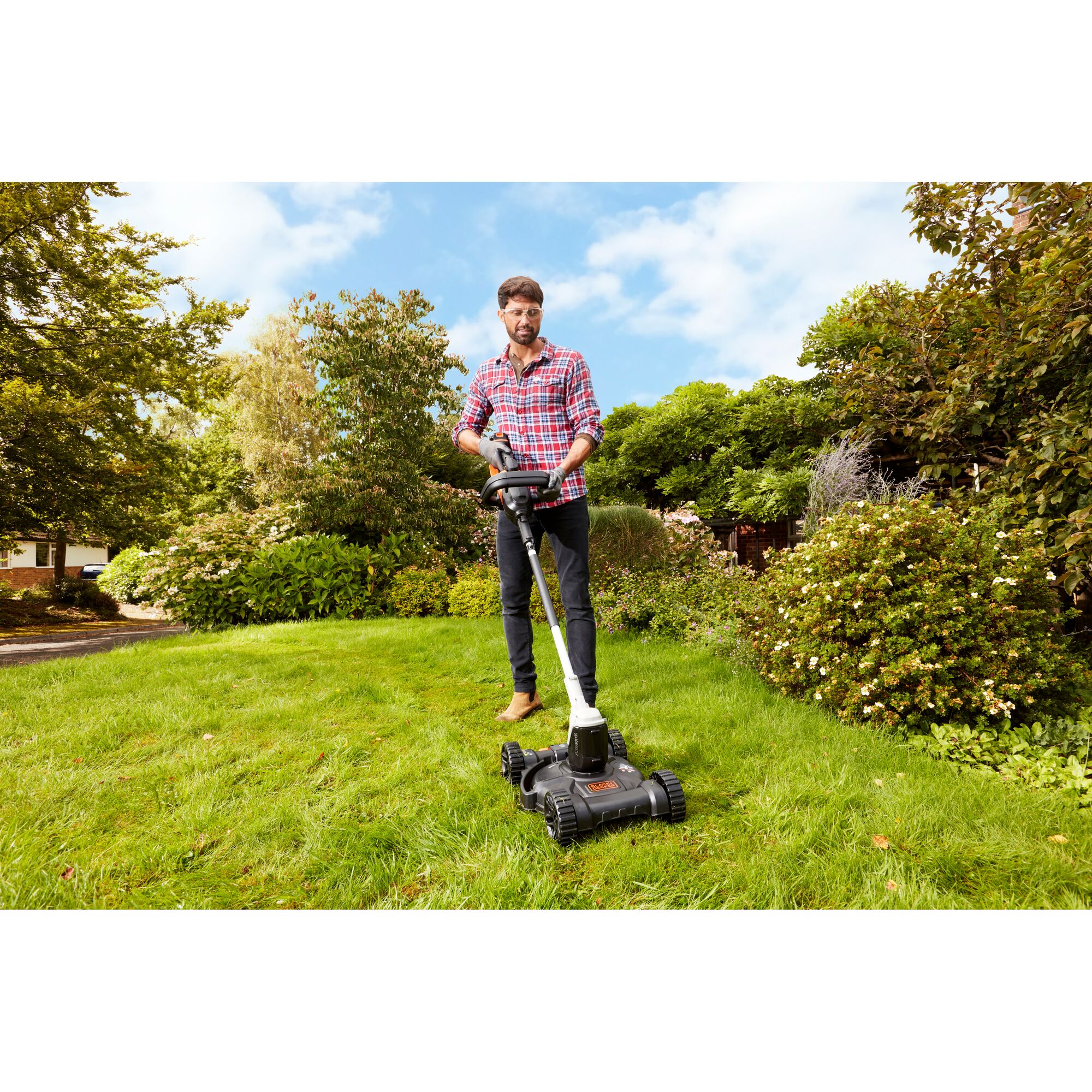 BLACKDECKER CM100 lawn mower being used on green grass outdoors.