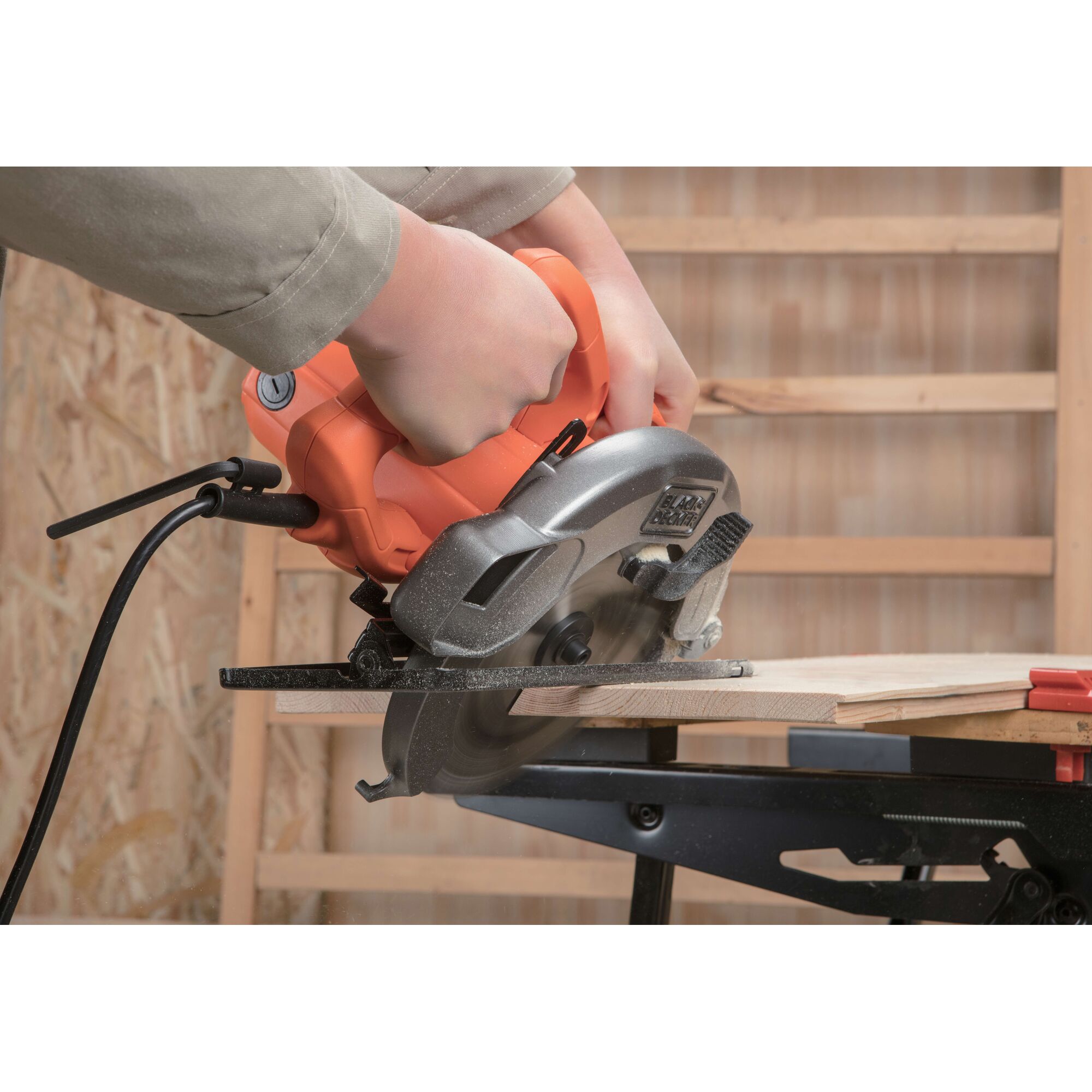 BLACKDECKER CS1004 circular saw cutting wood, handheld, orange and silver body, workshop setting.