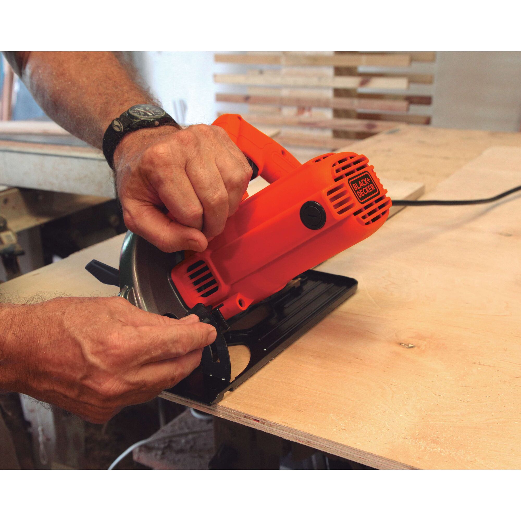 BLACKDECKER CS1004 circular saw being adjusted on plywood in a workshop setting.