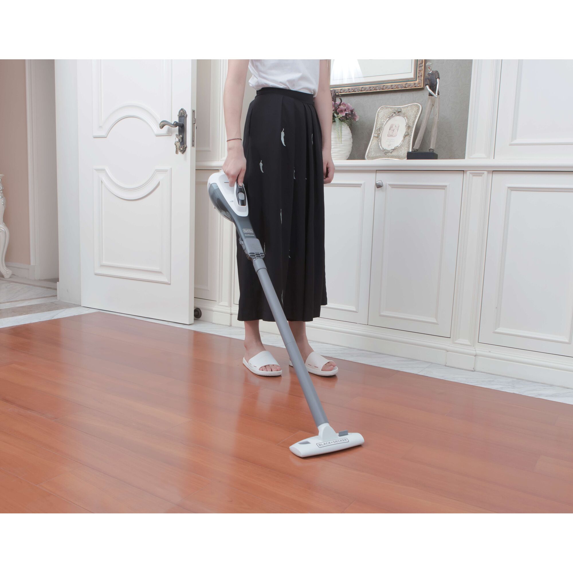 BLACKDECKER DVA315JF stick vacuum cleaner in use on wooden floor in home setting.